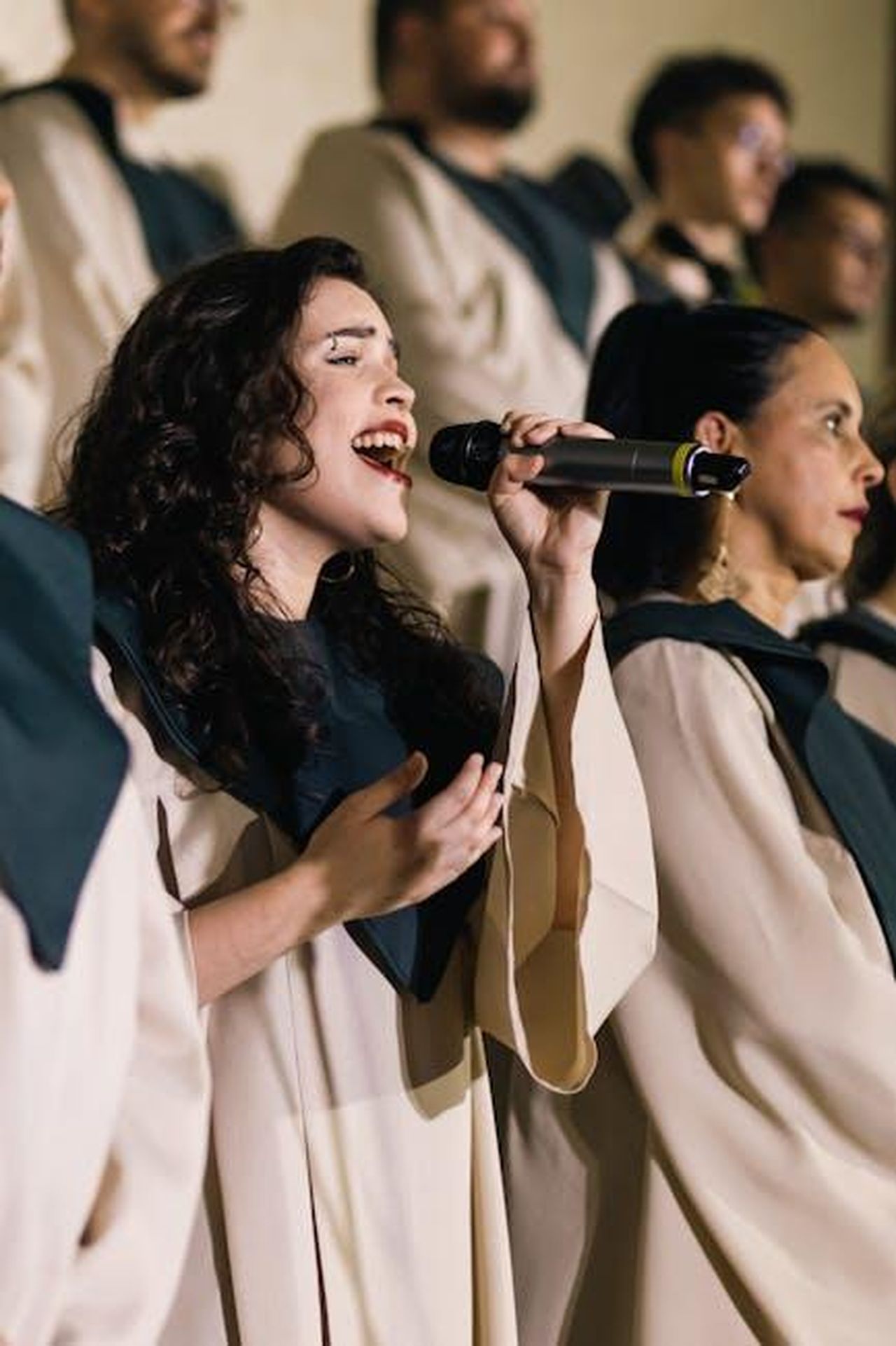 Il_ruolo_in_Sopranos_e_la_sua_importanza_BVo2azXr8L - Confidenze24 Source: SAULO LEITE - pexels - Woman singing with a choir, passionately holding a microphone. Captured in mid-performance with focused expression.