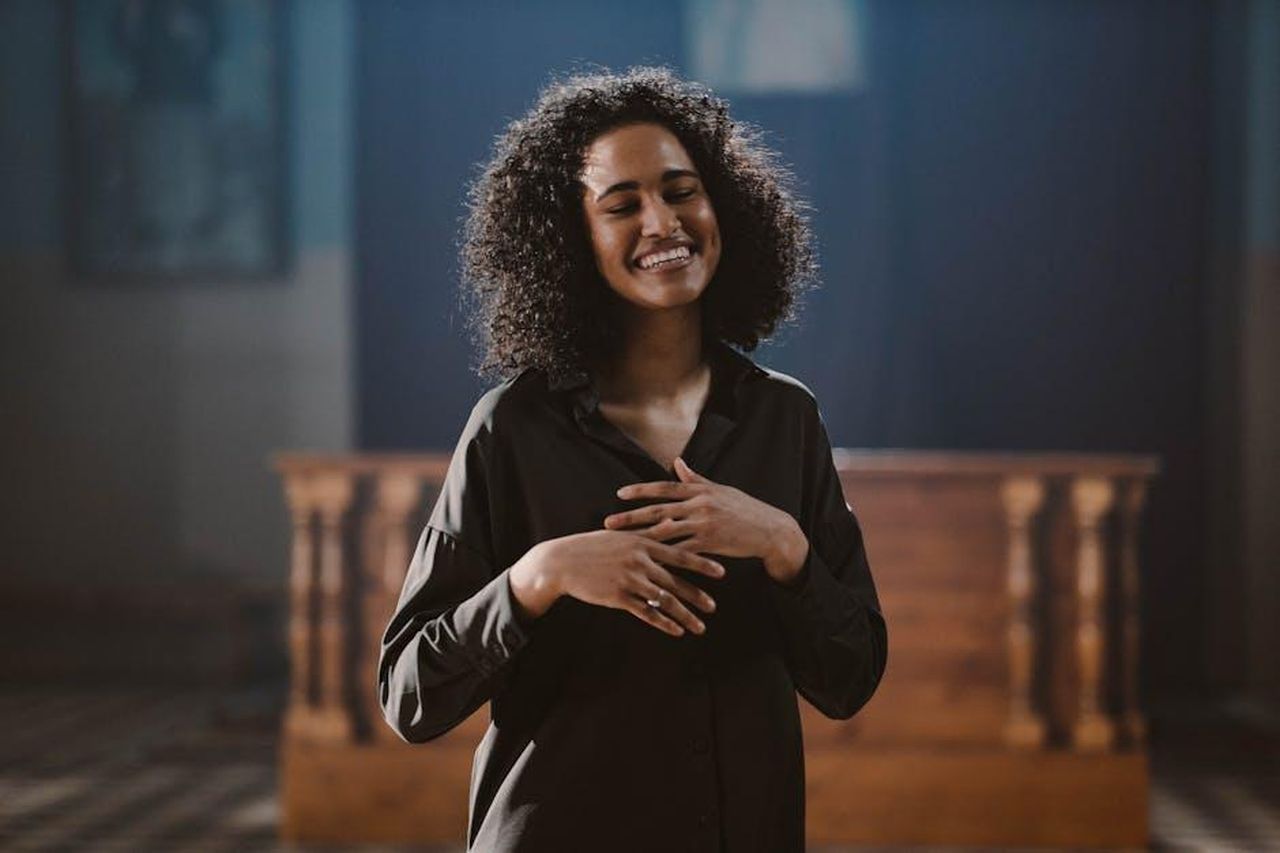 Il_significato_della_canzone_If_You_Hadnt_Been_There_ftYuBjd6r0 - Confidenze24 Source: cottonbro studio - pexels - A joyful woman with curly hair singing passionately in a church setting.