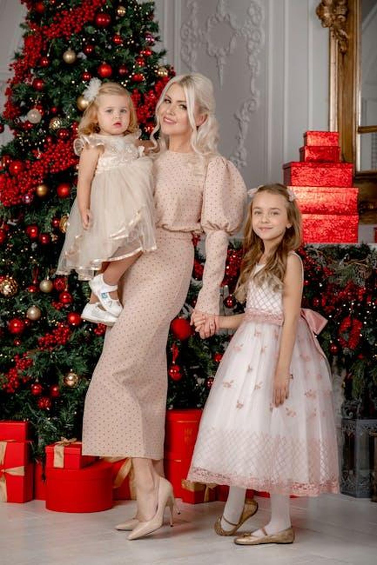 Il_vestito_coordinato_per_mamma_e_figlia_0OLLKoDcmL - Confidenze24 Source: Анна Хазова - pexels - Elegant family portrait with Christmas tree and gifts in an indoor setting.