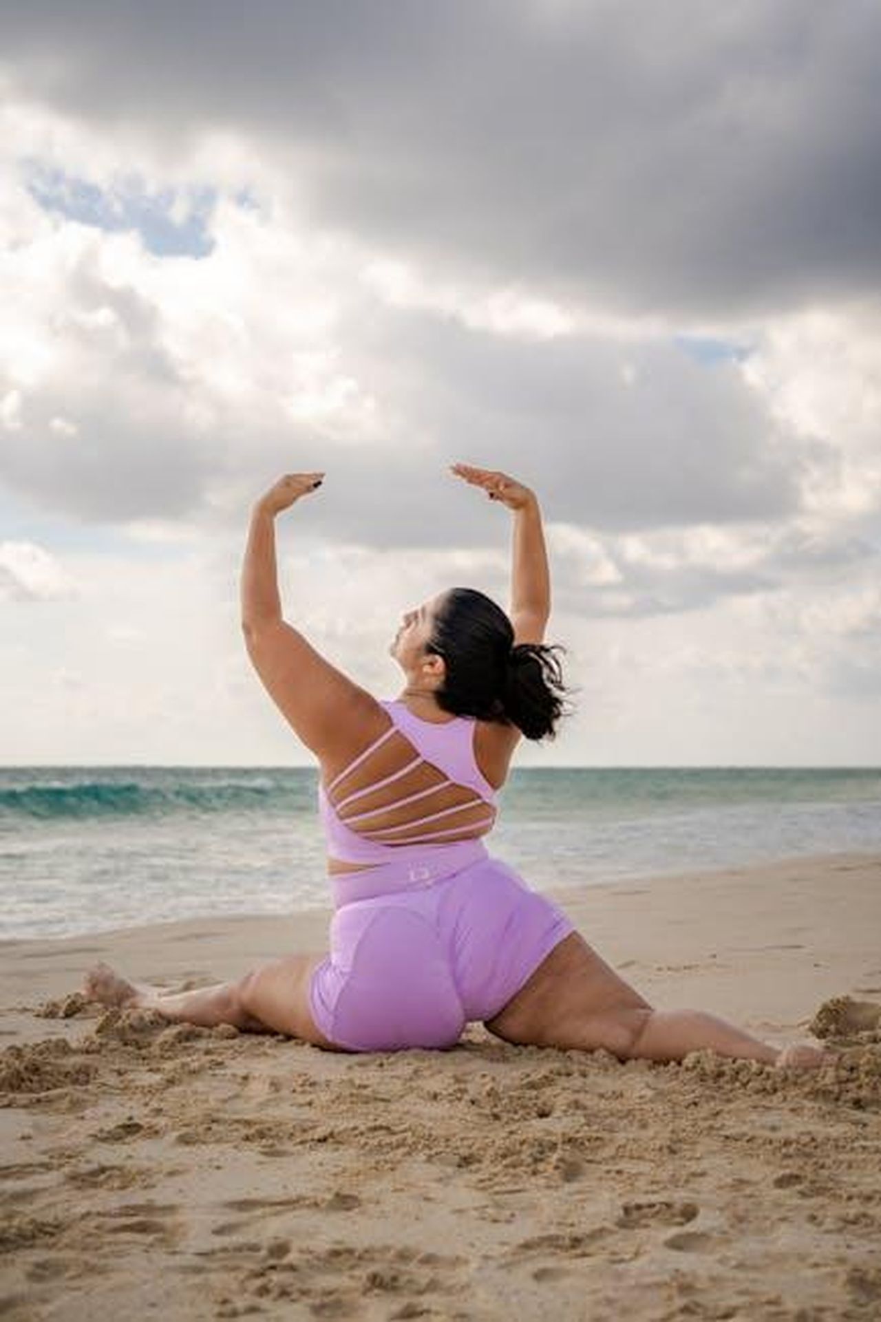 Il_viaggio_di_Lizzo_verso_la_salute_e_laccettazione_KPwLyIN4Ne - Confidenze24 Source: FbyF Studio - pexels - A woman performs yoga on a sandy beach, showcasing strength and flexibility in a serene coastal environment.