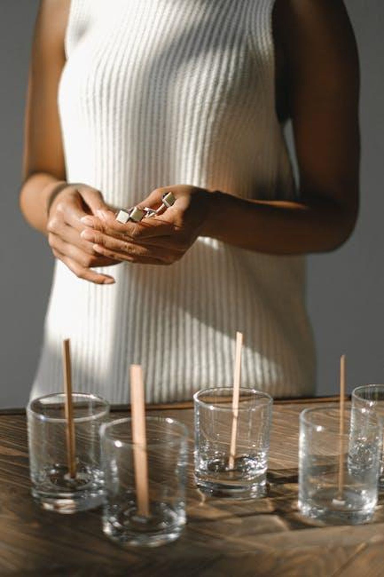 Incontro_sul_set_di_Wicked_e_i_primi_rumors_UuPl5q7MKJ - Confidenze24 Source: Anna Shvets - pexels - A woman preps homemade candles on a wooden table in a well-lit room, focusing on creativity and crafting.