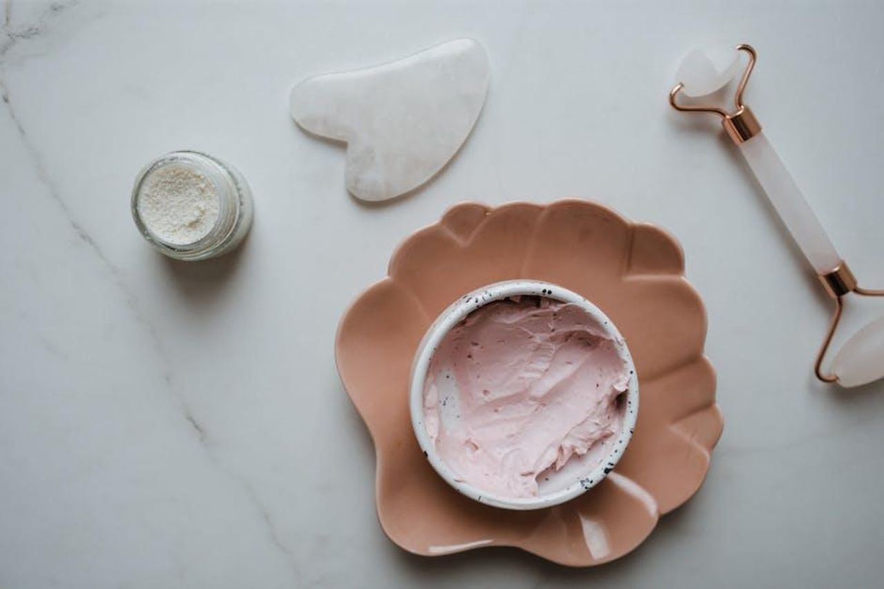 Ingredienti_chiave_del_TruSkin_Vitamin_C_Serum_KOLk5PmXBT - Confidenze24 Source: Polina ⠀ - pexels - Elegant top view of skincare essentials including cream, gua sha, and roller on marble surface, perfect for beauty concepts.