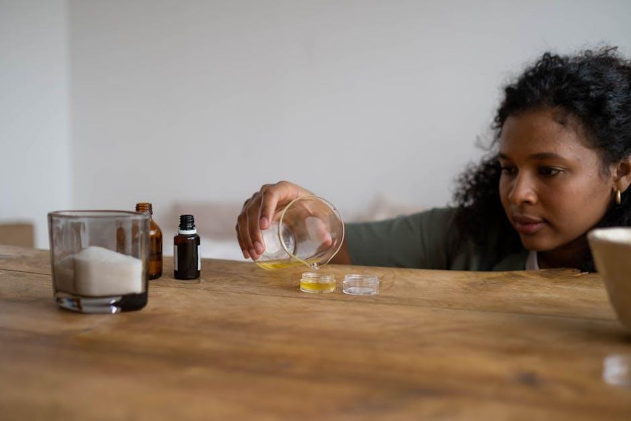 Ingredienti_chiave_del_Wet_n_Wild_Lip_Oil_hYailh2PQv - Confidenze24 Source: Ron Lach - pexels - A woman mixes ingredients to create natural lip balm indoors, using a wooden table as a workspace.