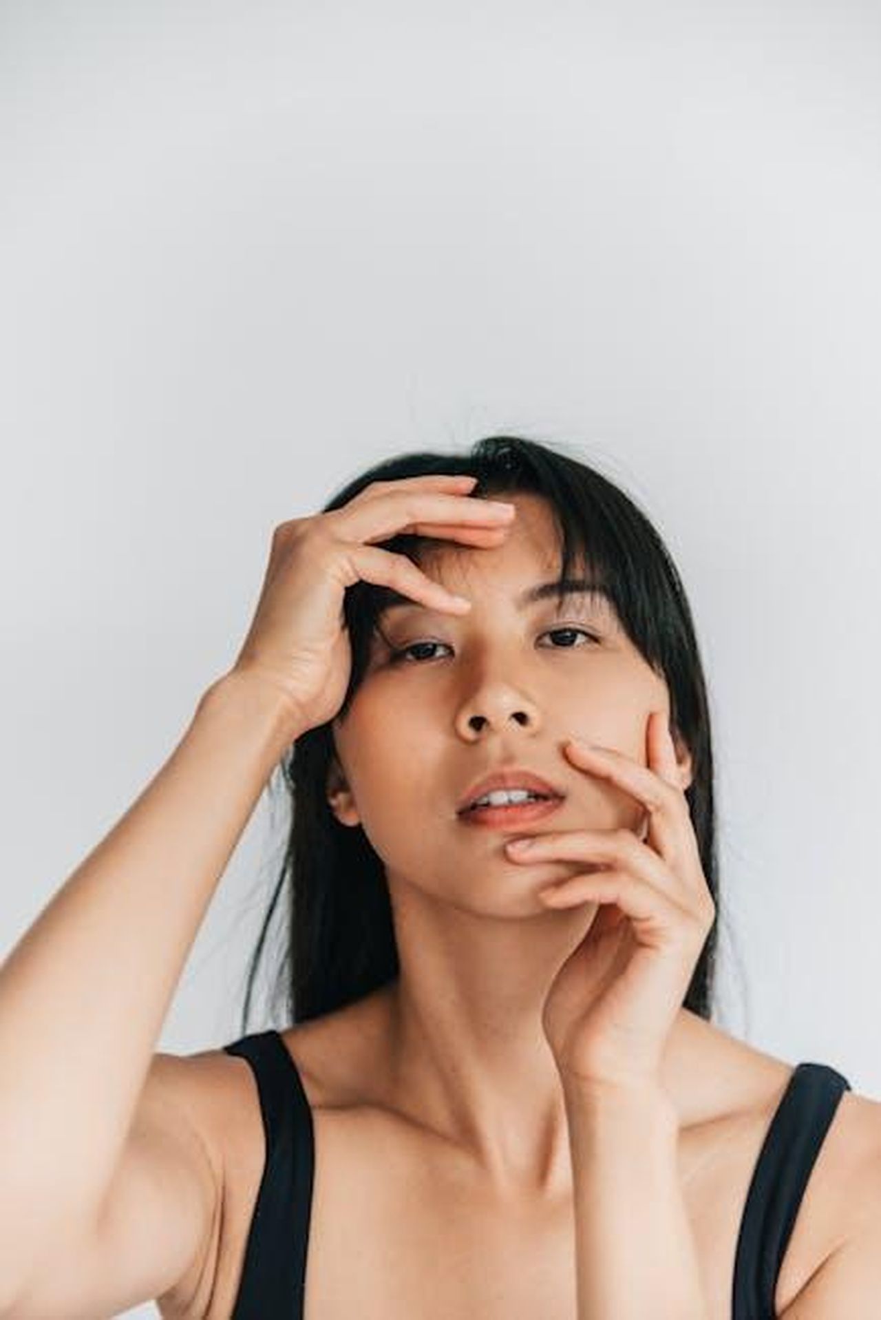 Ingredienti_e_benefici_del_balsamo_detergente_7PtsNiYdN9 - Confidenze24 Source: PNW Production - pexels - A stunning minimalist portrait of a woman posing with hands on her face in a studio setting.