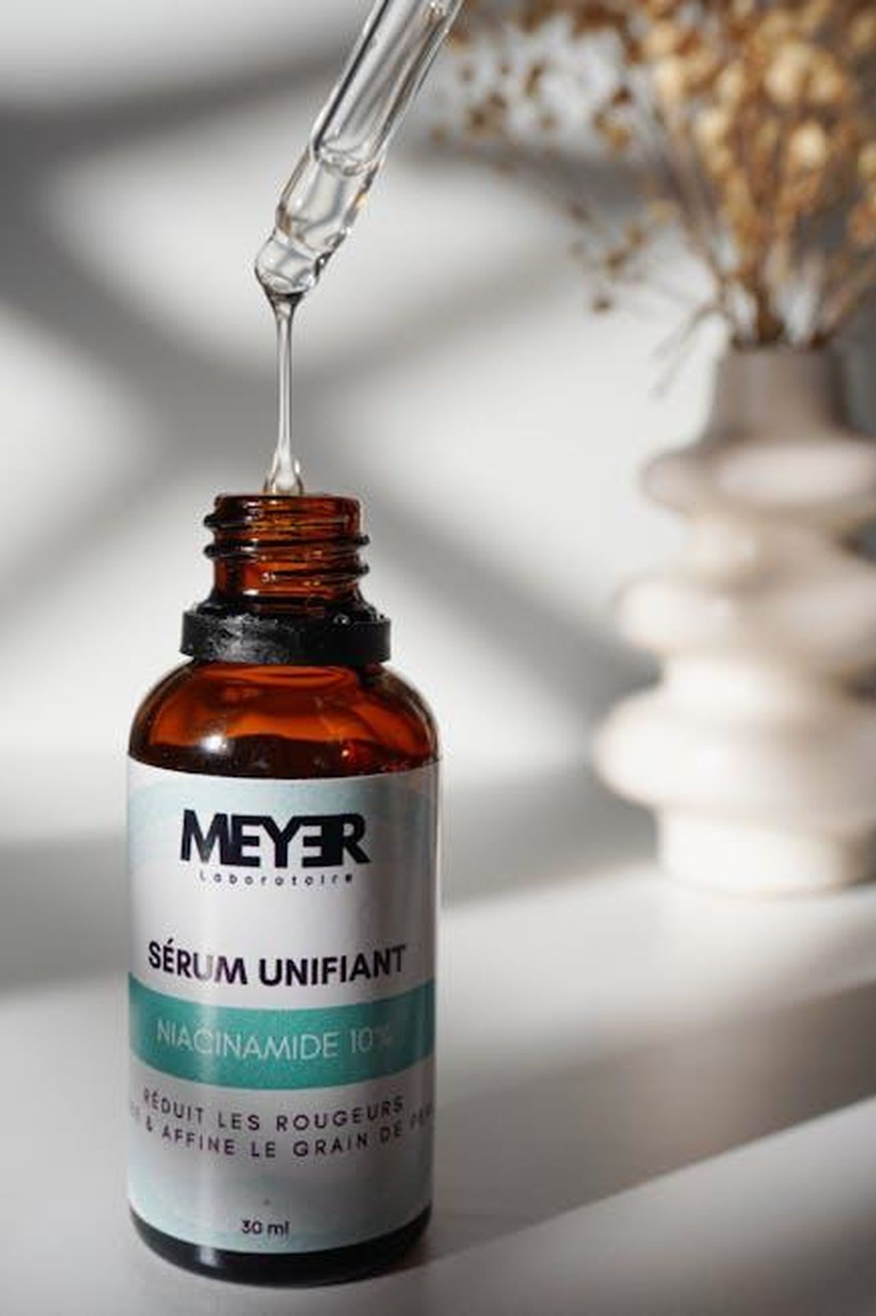 Ingredienti_e_benefici_del_bronzing_serum_F8QZ4JdW3o - Confidenze24 Source: anfel lanane - pexels - Close-up of a niacinamide serum bottle with dropper against a soft background.