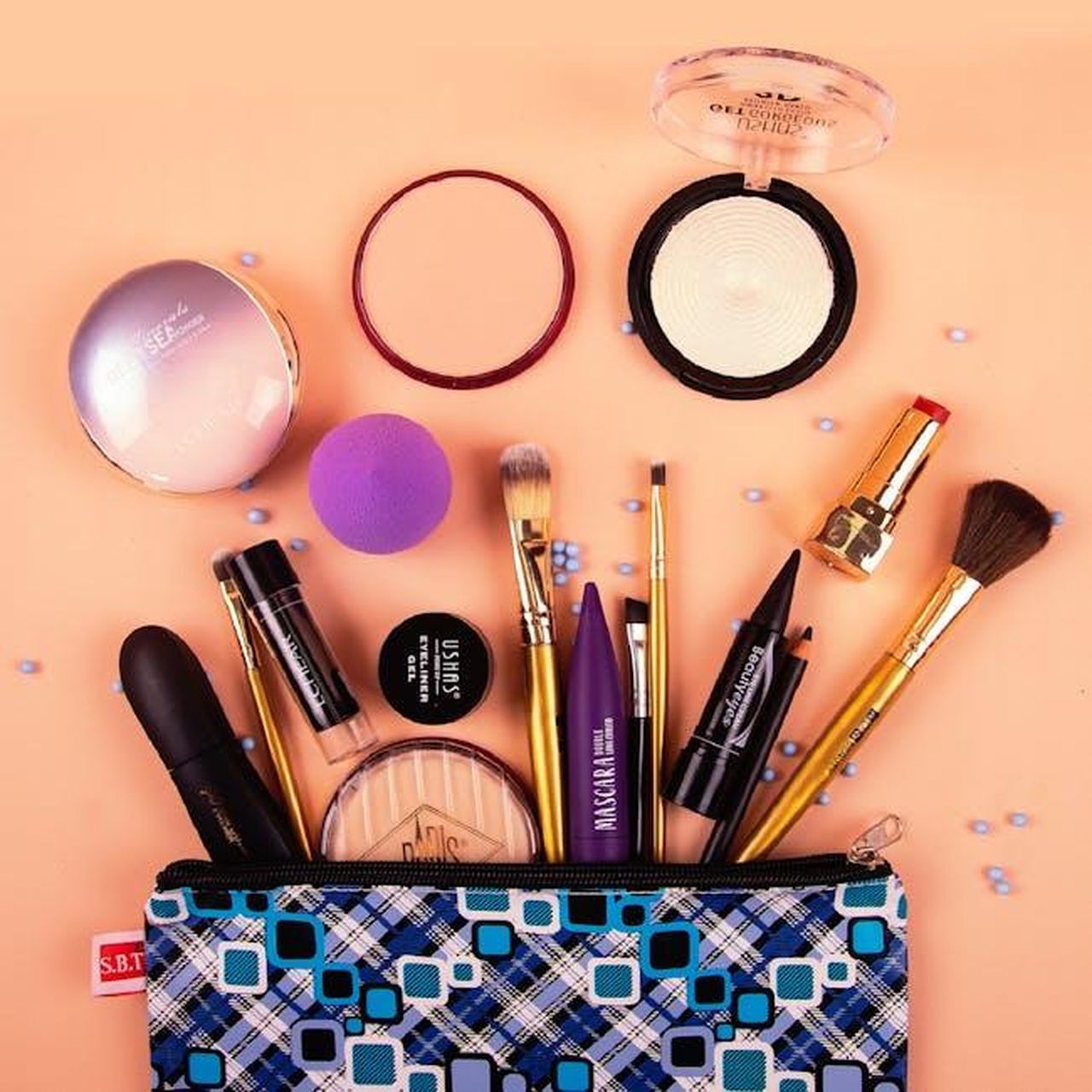 Ingredienti_e_formula_del_rossetto_T2zUDbKqVO - Confidenze24 Source: Jhong Pascua - pexels - A vibrant assortment of makeup tools and products stylishly arranged on a peach background.
