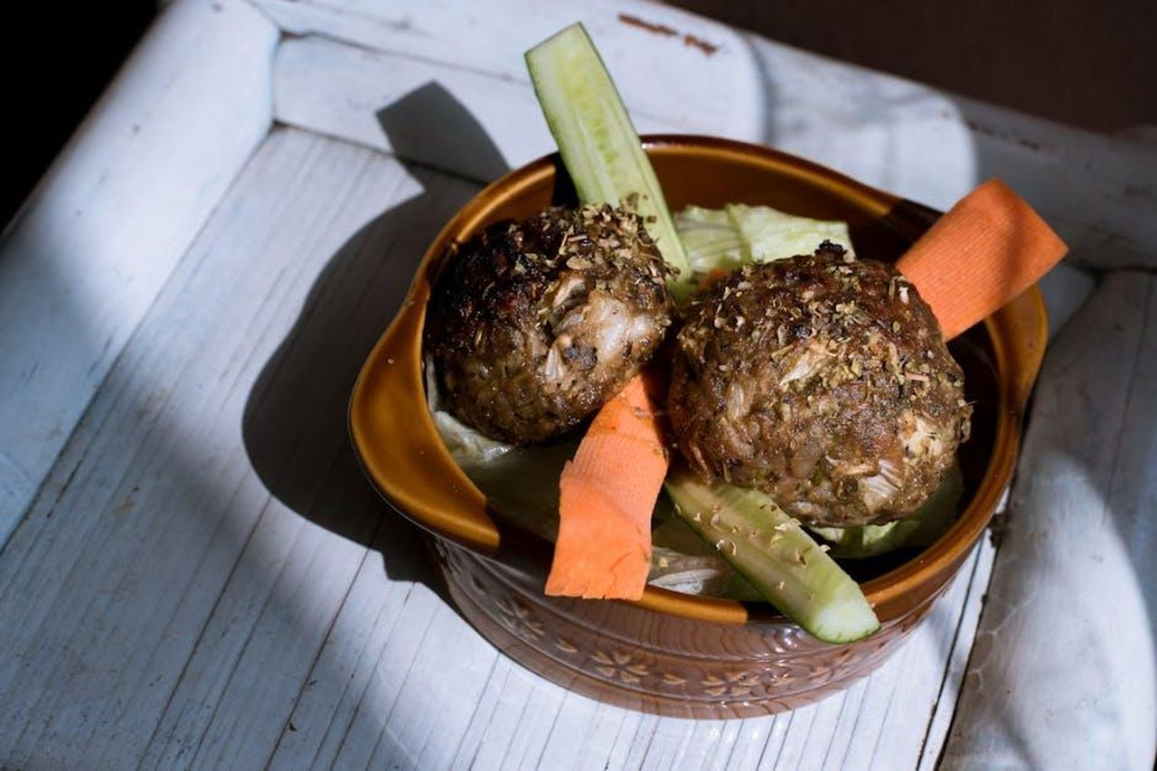 Ingredienti_e_preparazione_delle_polpette_6GOQdWcTBg - Confidenze24 Source: Abby Chung - pexels - Savory homemade meatballs with fresh cucumber and carrot slices in a rustic bowl.