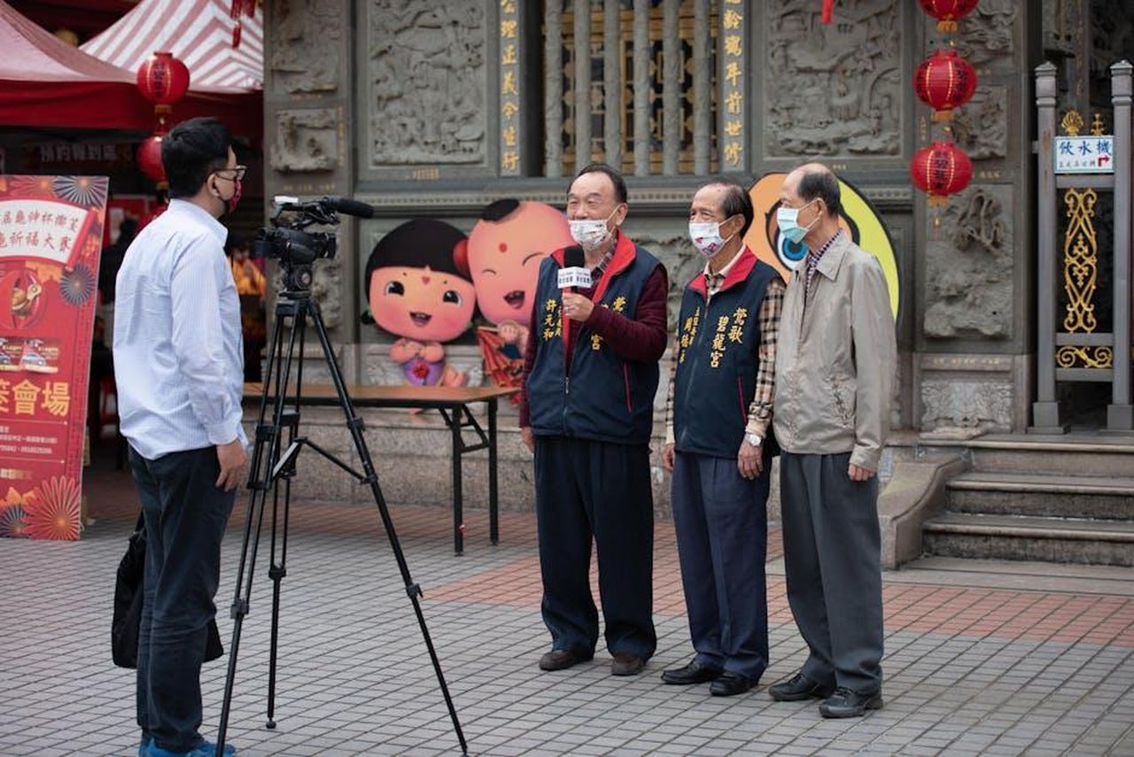 Intervista_a_Fiona_Rene_su_Randy_e_Bobby_V3qLNAVpYy - Confidenze24 Source: Max Chen - pexels - Elderly men wearing face masks being interviewed outdoors with festive decorations in the background.
