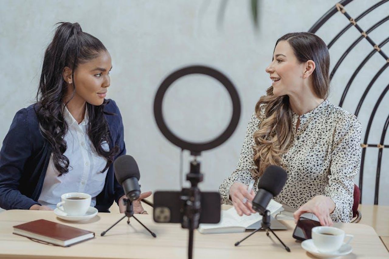 Interviste_e_ospiti_speciali_nel_podcast_xAGfte6tTe - Confidenze24 Source: George Milton - pexels - Positive blogger asking questions to African American speaker and recording interview on cellphone at table with microphones