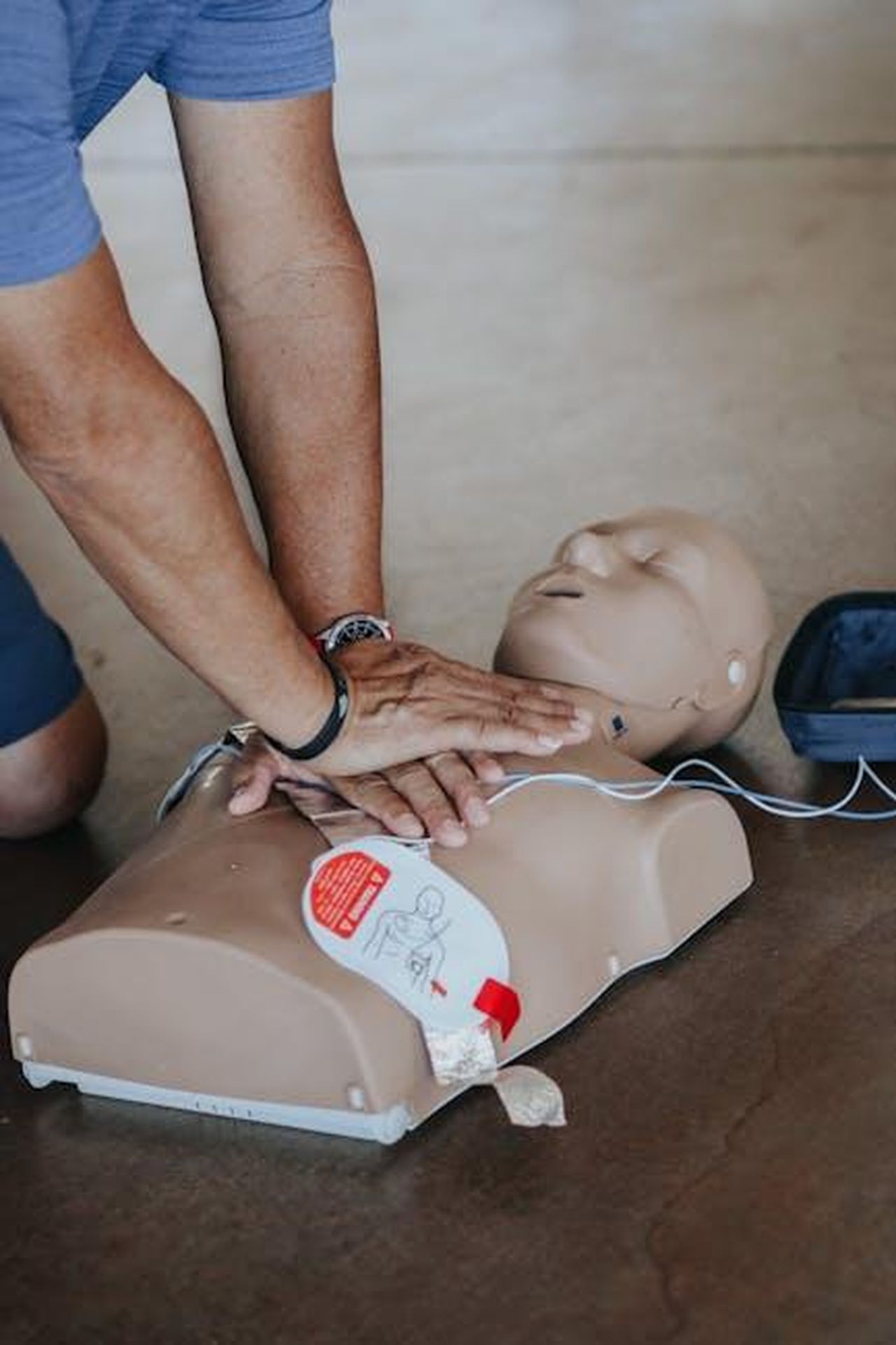 Jakes_Ha_Dichiarato_di_Essere_Potuto_Morire_Se_Avrebbe_Aspettato_per_Ricevere_Assistenza_Medica_SsXw9sFcx0 - Confidenze24 Source: Raven Domingo - pexels - Hands demonstrating CPR technique on a training mannequin with AED.