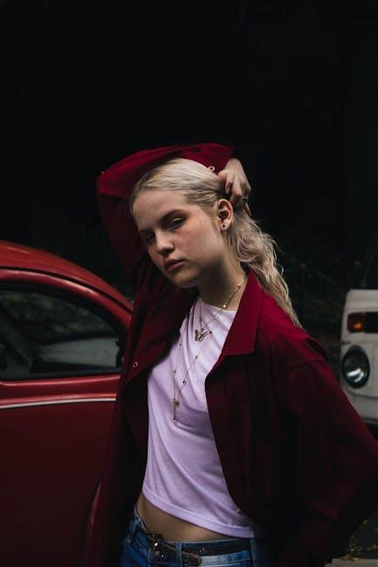Jeans_We_The_Free_stili_popolari_e_scontati_oKWj1Ocfpg - Confidenze24 Source: VICTOR SANTOS - pexels - Stylish woman in casual attire poses confidently near vintage cars. Fashion vibe captured outdoors.