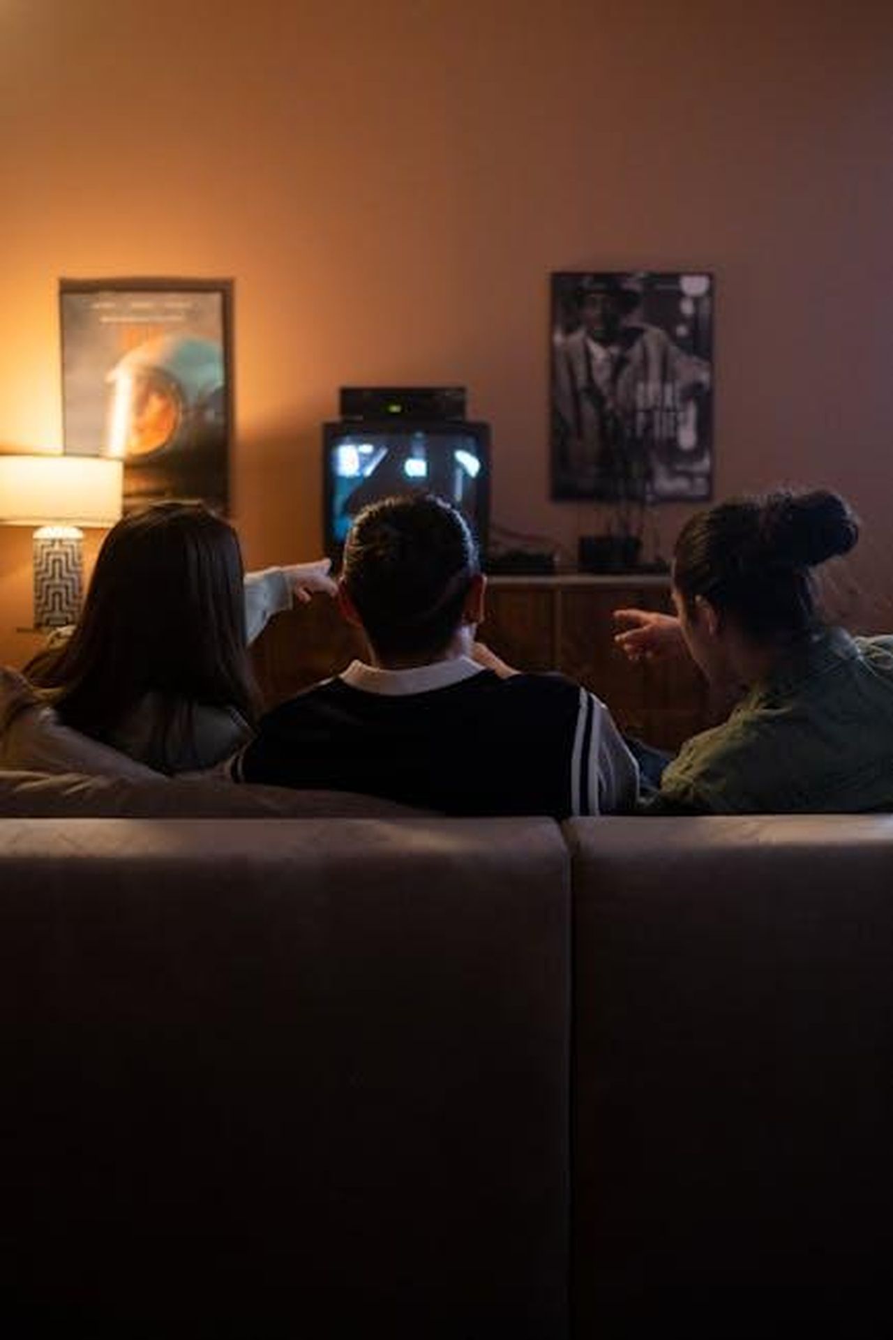 Josie_sostituisce_Alison_su_This_Morning_9b9wS1B6Ih - Confidenze24 Source: Ron Lach - pexels - Three friends sitting on a couch enjoy a cozy movie night together, pointing at the TV screen.