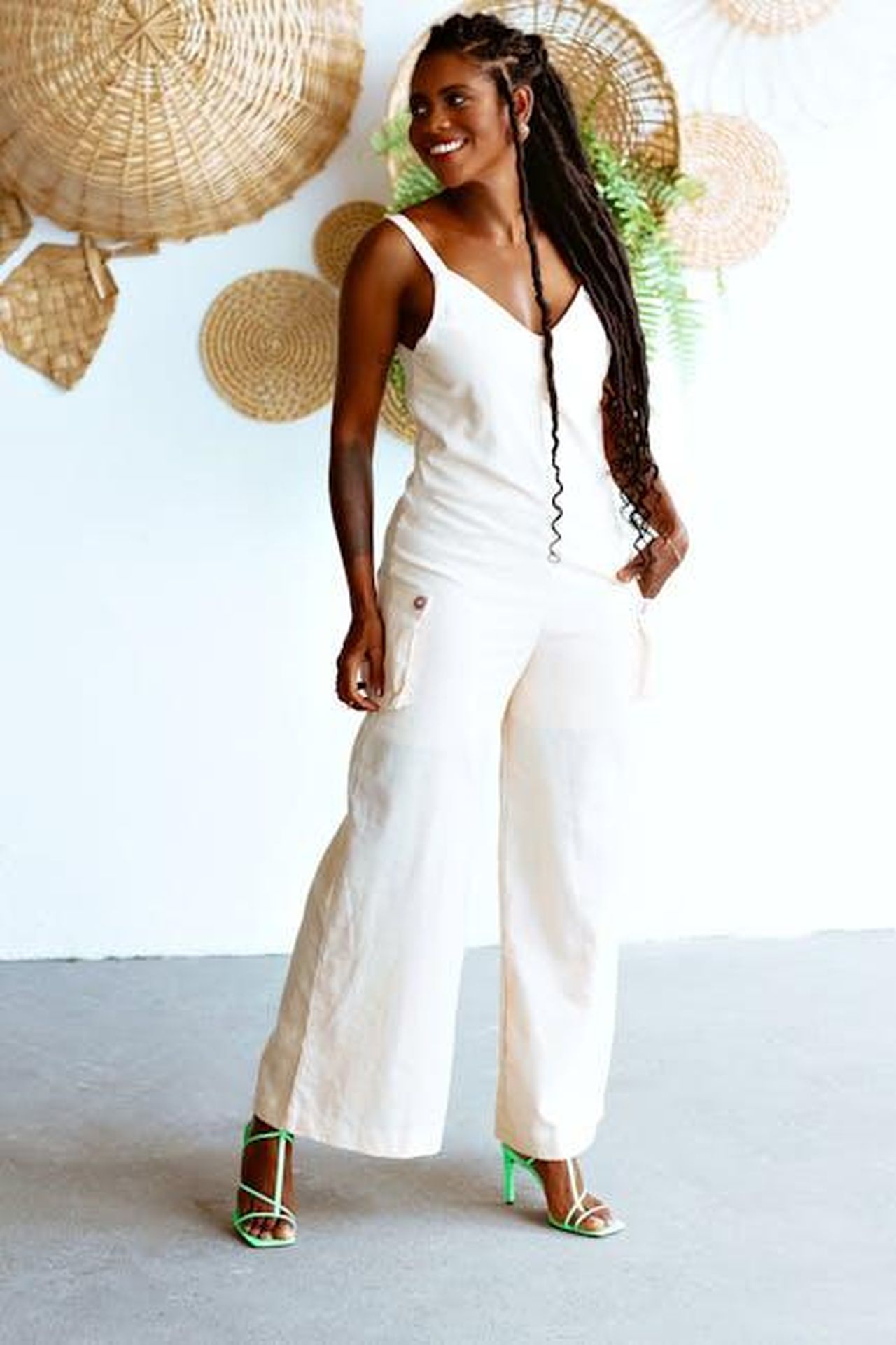 Jumpsuit_wide_leg_in_jersey_Tencel_lZUjYqXfAV - Confidenze24 Source: Lucas Andrade - pexels - A fashionable woman with braided hair smiling elegantly in a bright, indoor setting.