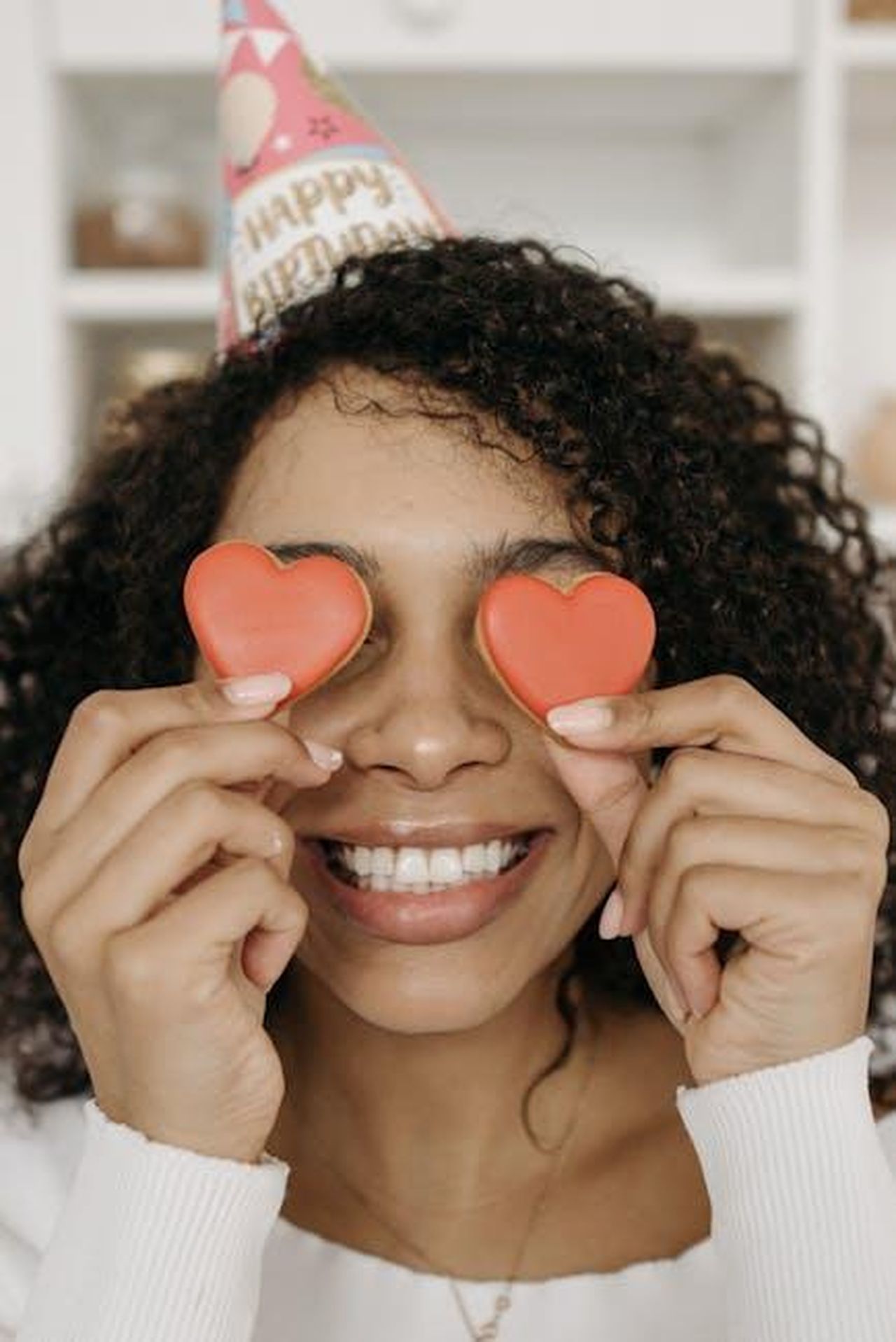 Kate_Garraway_uno_stile_di_cottura_entusiasta_K04DcgzAsN - Confidenze24 Source: Pavel Danilyuk - pexels - Smiling woman celebrating birthday with heart-shaped cookies covering her eyes.