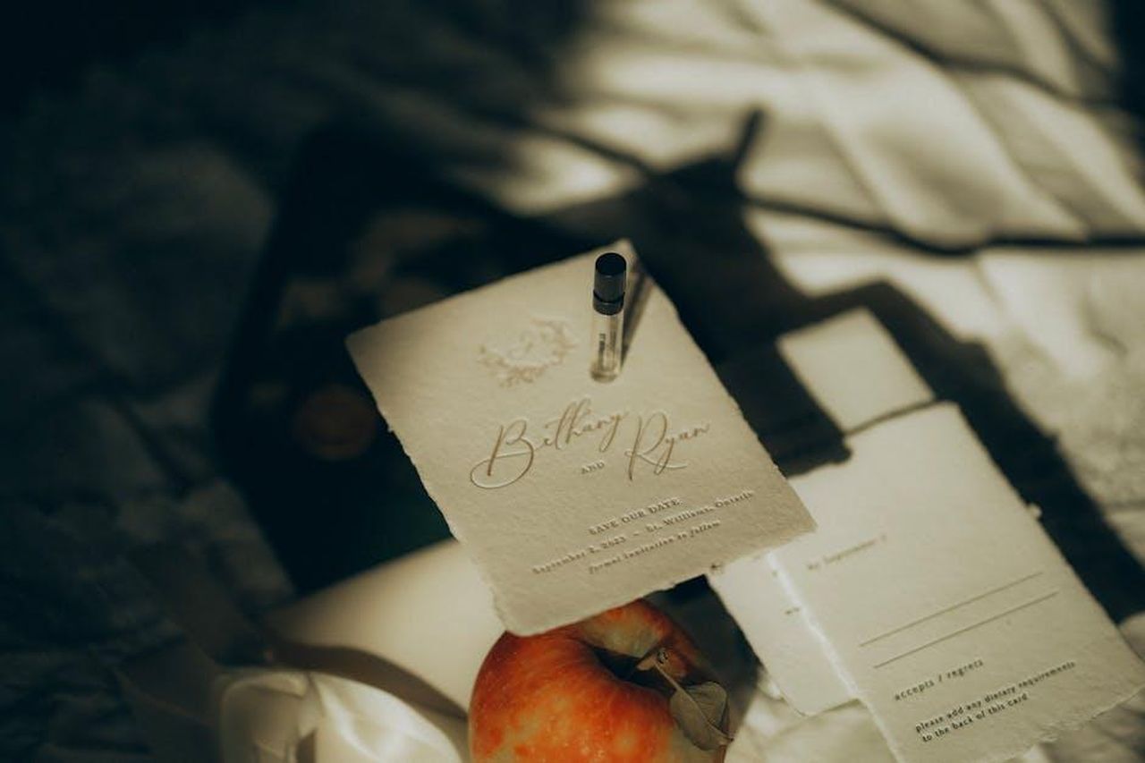 Katherine_Ryan_e_le_sue_frecciatine_sarcastiche_tlIIUoTdZd - Confidenze24 Source: Amoria Made - pexels - Artistic flat lay featuring an elegant save the date card with soft shadows, an apple, and a perfume vial.