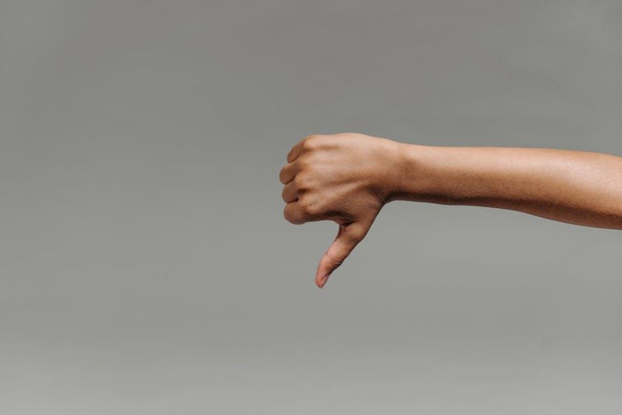 Katie_Price_criticata_per_i_nuovi_denti_6E5Y0Kiu5V - Confidenze24 Source: ROCKETMANN TEAM - pexels - Close-up of a person's hand giving a thumbs down gesture against a gray background.