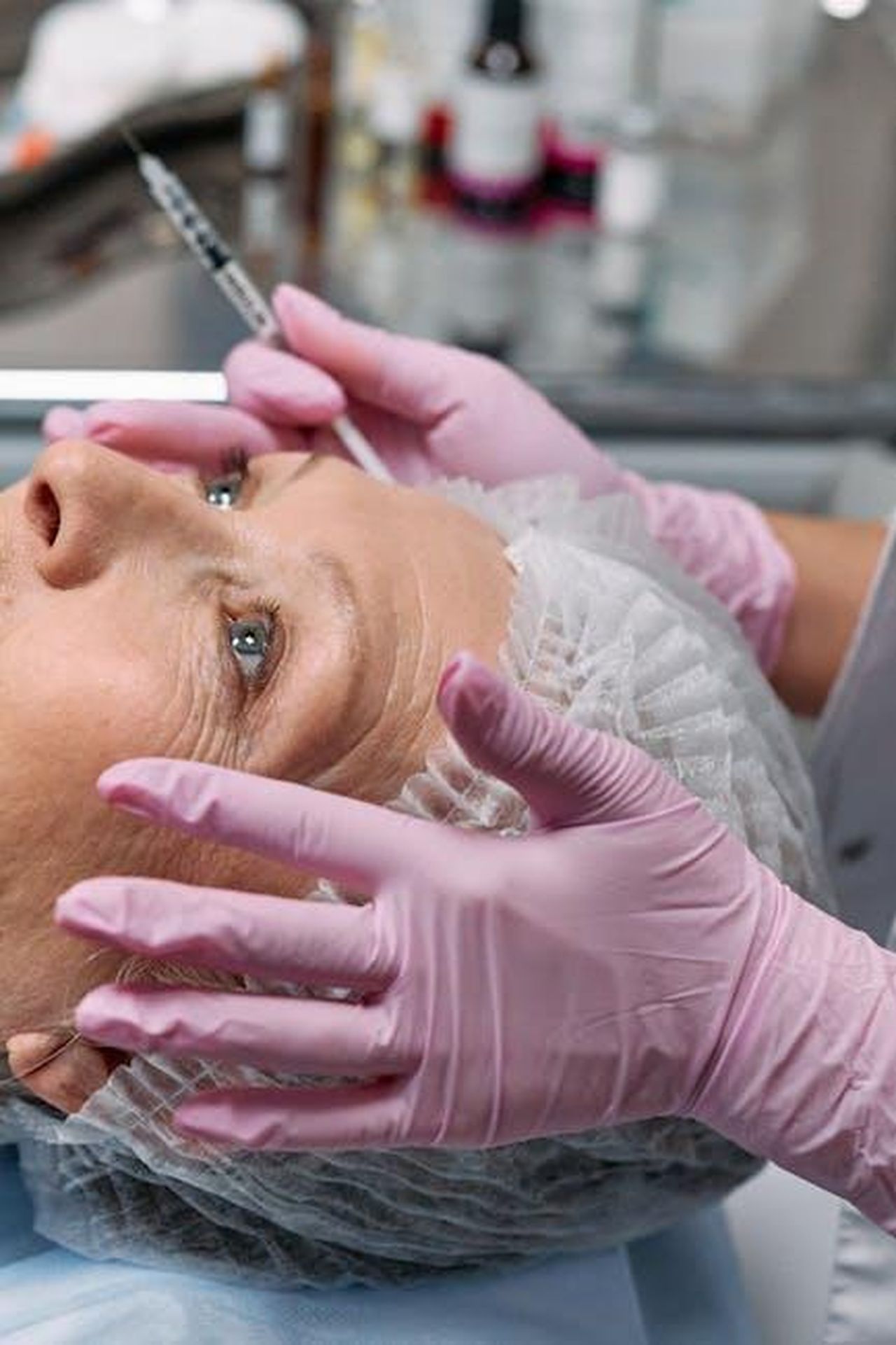 Katie_criticata_per_il_nuovo_lifting_NpCB5bK92J - Confidenze24 Source: cottonbro studio - pexels - Close-up of a senior woman receiving a cosmetic injection in a clinical setting with gloves and a hairnet.