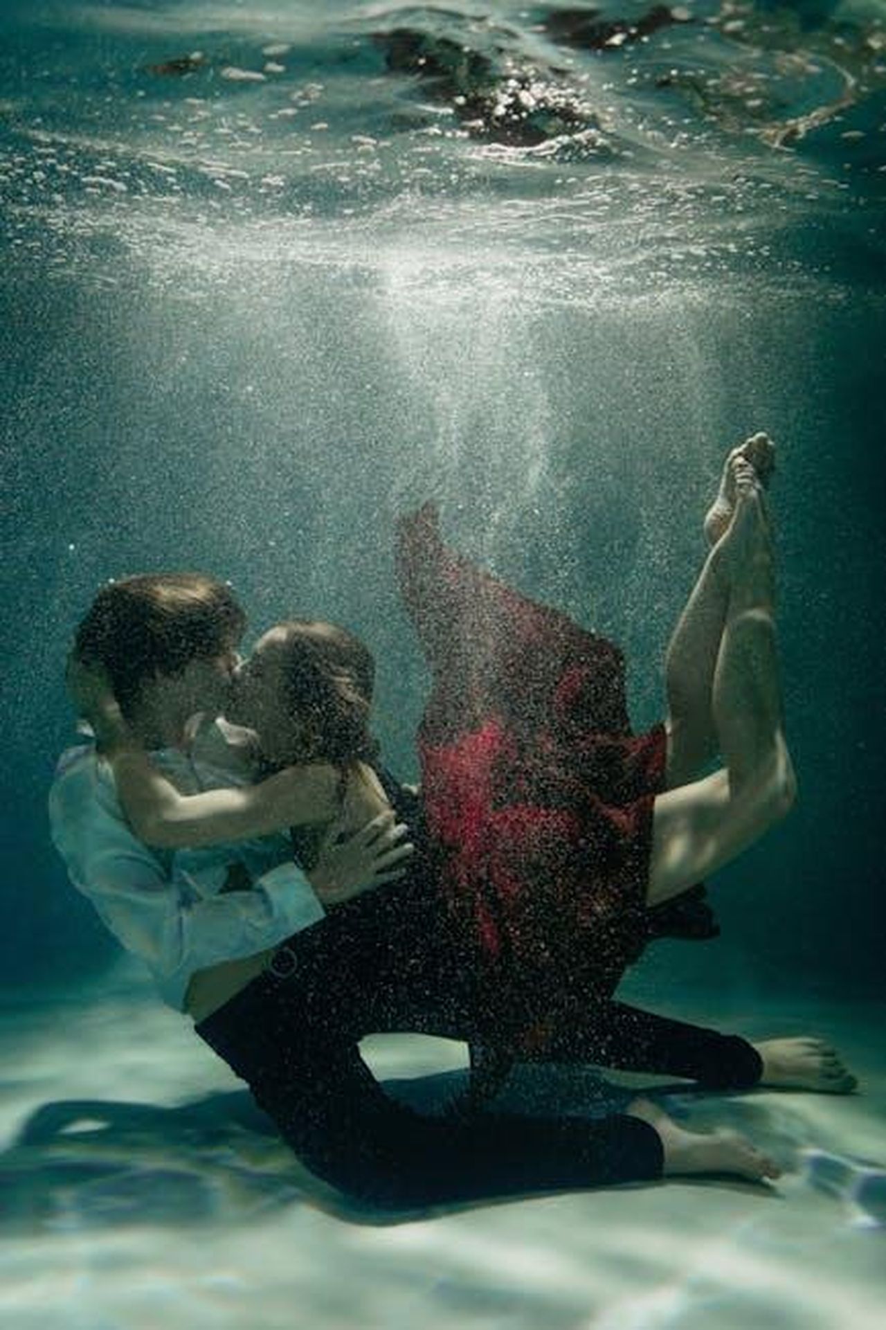 La_Drammatica_Situazione_della_Relazione_xyFygSpdSn - Confidenze24 Source: Victoria Strelka_ph - pexels - Artistic underwater photo of a couple embracing in red and white attire, conveying love and passion.