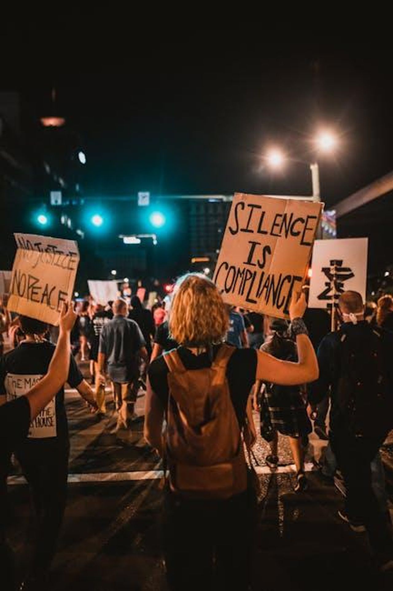 La_Risposta_di_Umar_Johnson_alle_Accuse_35wiypQUg3 - Confidenze24 Source: Kelly - pexels - Activists gather at night for a protest in the city, holding signs and expressing their message.