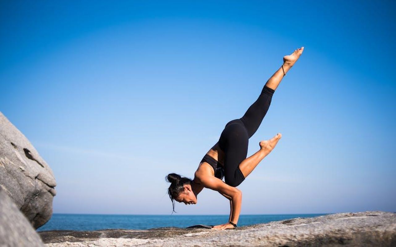 La_Situazione_Sanitaria_di_Tim_McGraw_VB55Se8nRY - Confidenze24 Source: Chevanon Photography - pexels - Woman performing a yoga pose on a rocky beach with ocean view and clear blue sky.