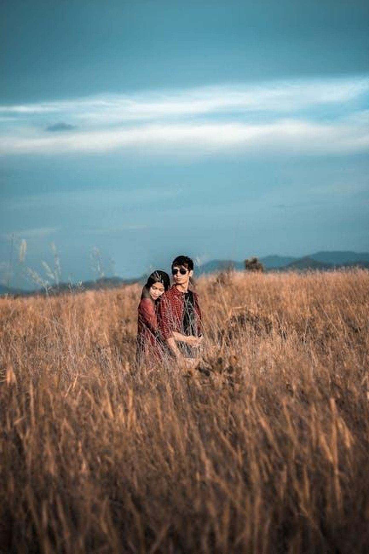 La_Storia_dAmore_tra_Elton_John_e_David_Furnish_jPJIqmMpOX - Confidenze24 Source: Padli Pradana - pexels - A young couple embraces in a peaceful hayfield, surrounded by golden grass under a bright blue sky.