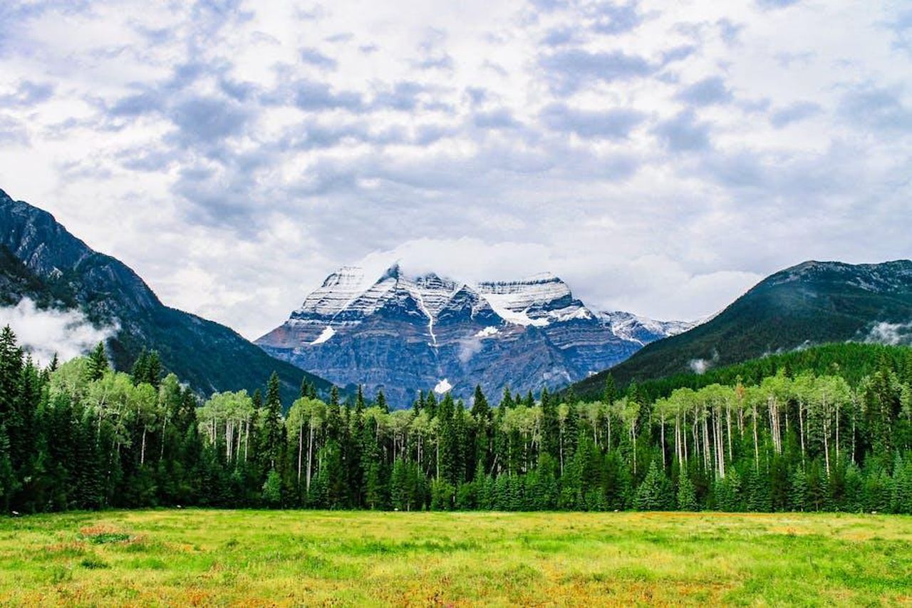 La_bellezza_naturale_di_Kris_0osRLVNkSq - Confidenze24 Source: Baskin Creative Co. - pexels - A scenic view of a snow-capped mountain surrounded by lush green forests and a cloudy sky.