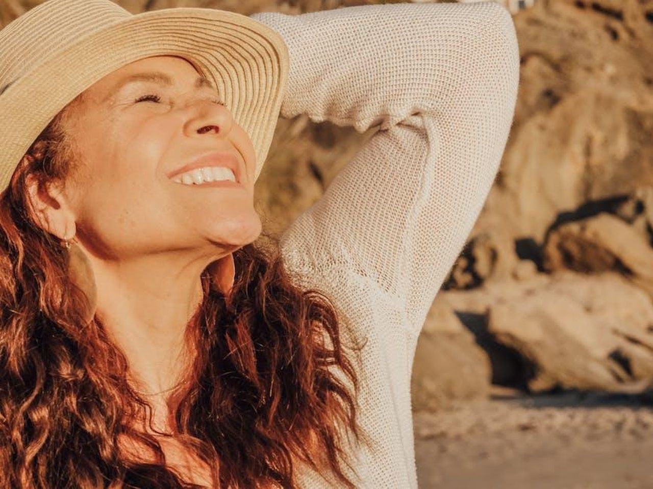 La_bellezza_oltre_i_ruoli_sexy_z0VwnozYFj - Confidenze24 Source: Kindel Media - pexels - A joyful woman with a hat basks in the sunlight by the seaside, symbolizing relaxation and happiness.