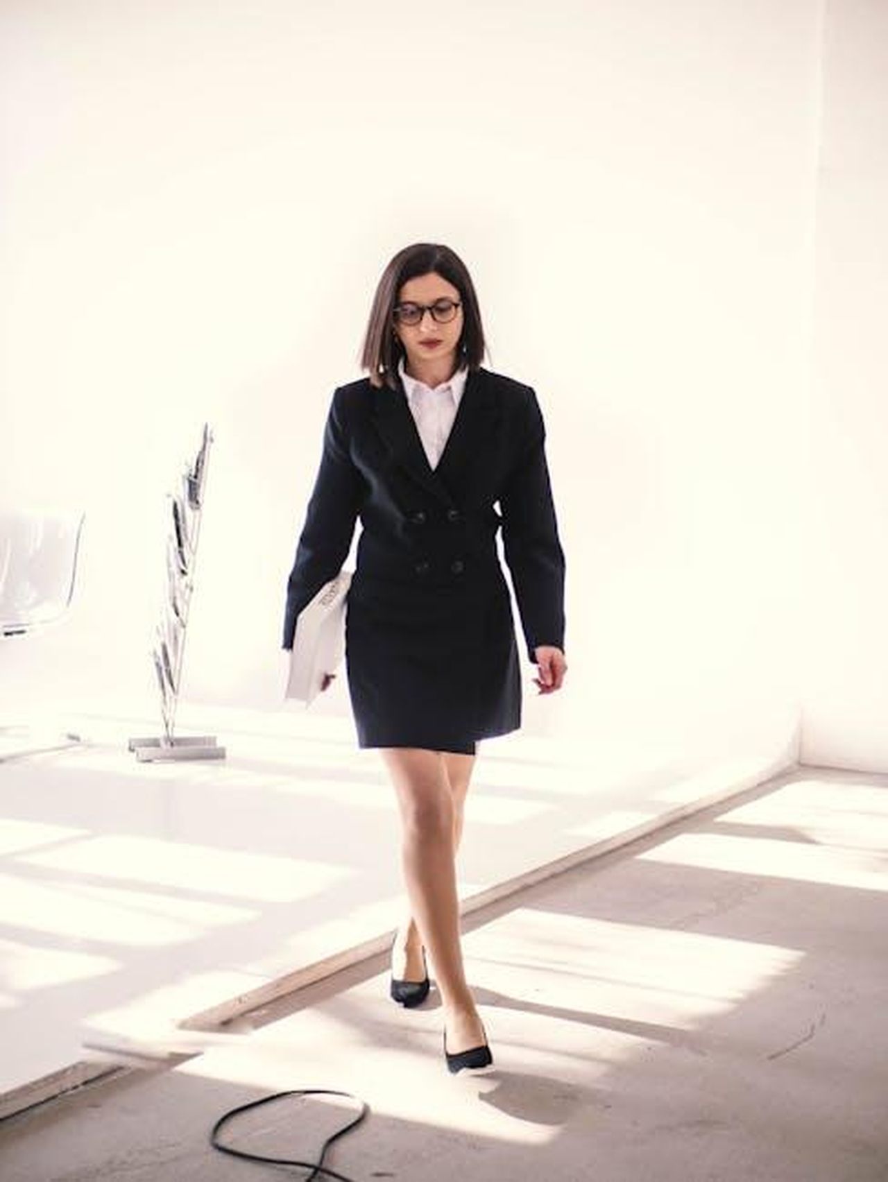 La_carriera_di_Robert_Redford_Tw4IjFLimo - Confidenze24 Source: QVEVRI TBILISI - pexels - Professional woman in tailored suit walks confidently in a sunlit modern office setting.