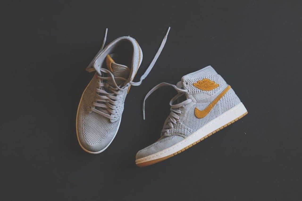 La_collezione_Dr_Scholls_x_Milk_Bar_Na9VGAd46r - Confidenze24 Source: Mnz - pexels - Close-up of fashionable gray and orange high-top sneakers displayed against a minimal background.