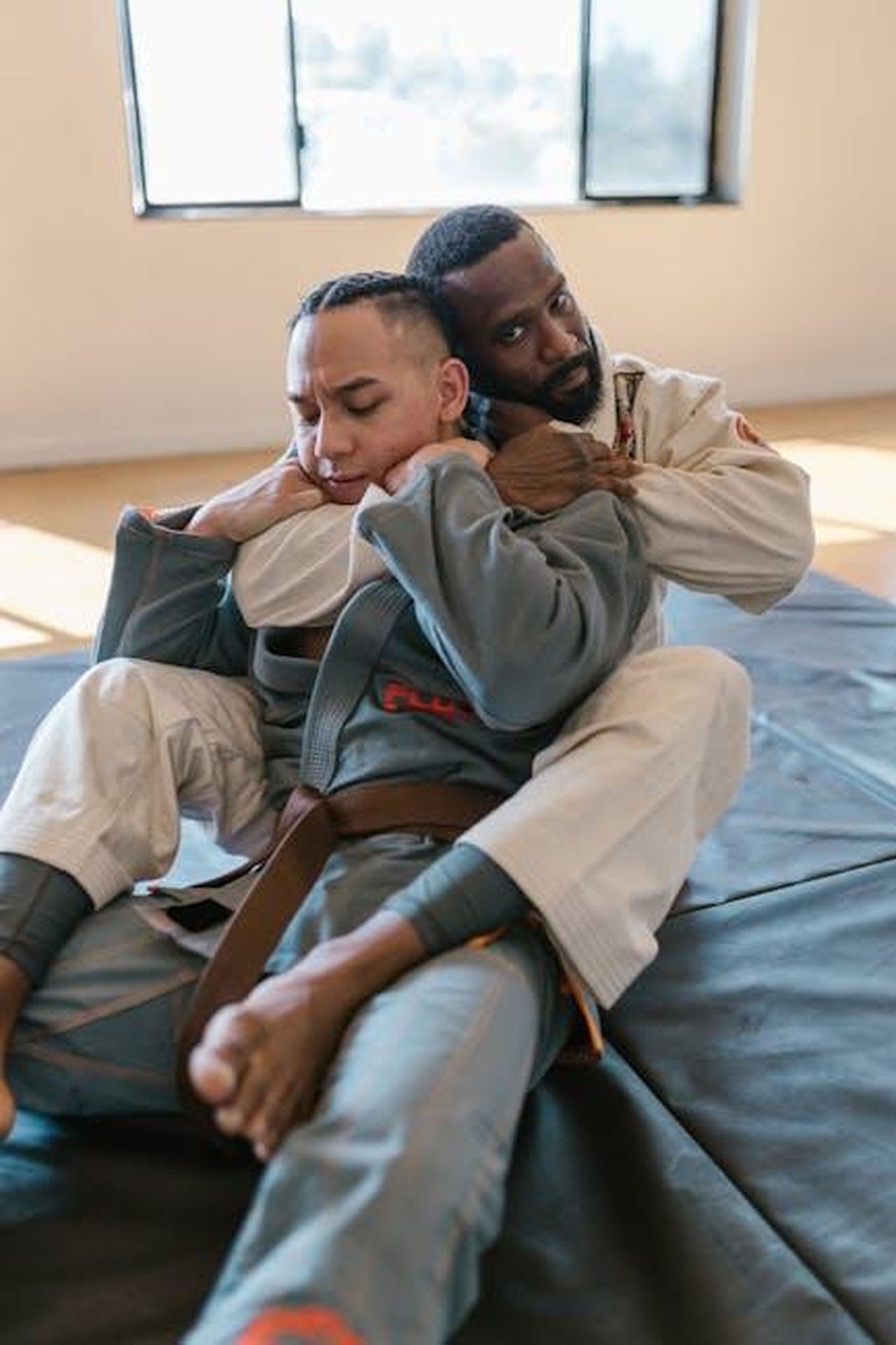 La_connessione_tra_Ivanka_Trump_e_i_Valente_Brothers_KaFtCc12n4 - Confidenze24 Source: RDNE Stock project - pexels - Two adult men engaged in jiu-jitsu training on indoor mats with focused expressions.