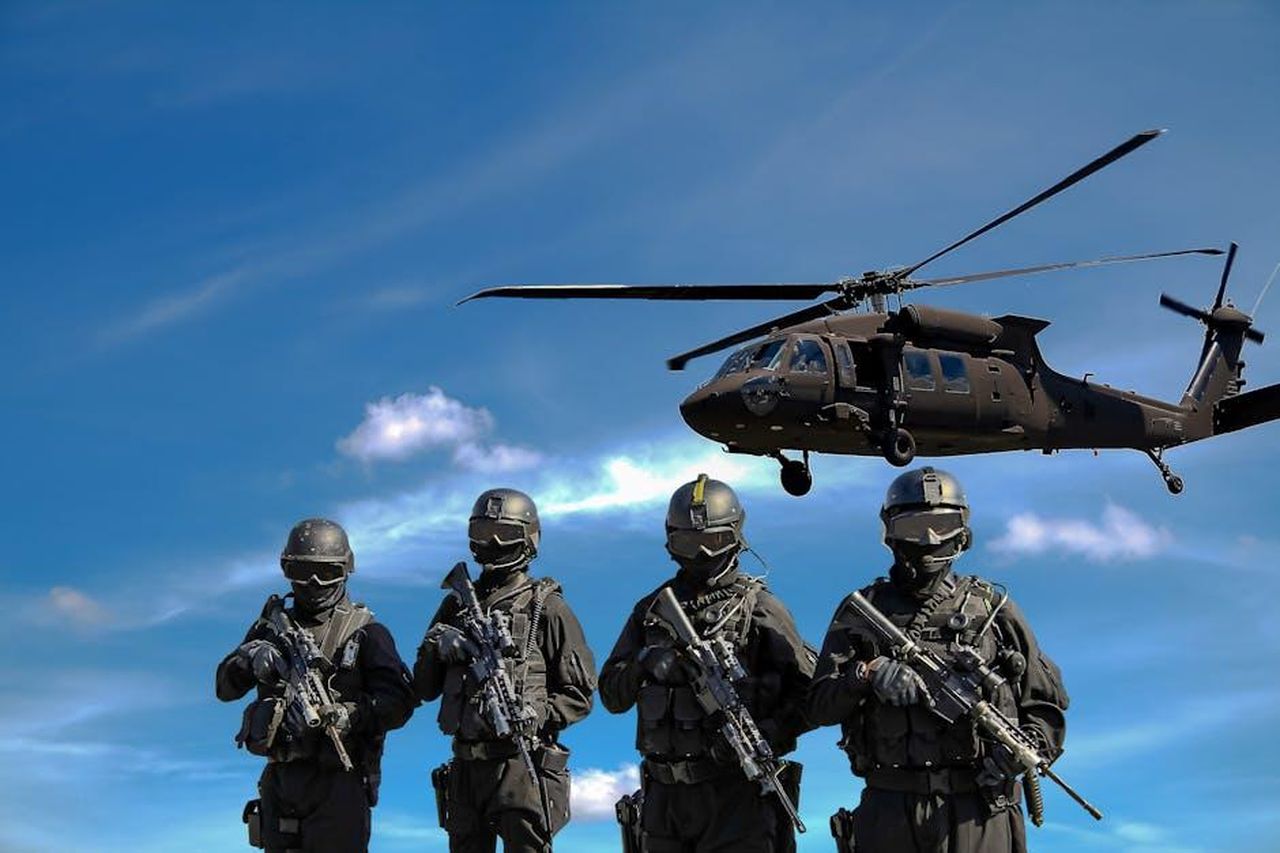 La_difesa_di_JayZ_e_la_controcausa_7mrsGFV1k7 - Confidenze24 Source: Somchai Kongkamsri - pexels - Special forces soldiers in tactical gear with helicopter overhead under a blue sky.