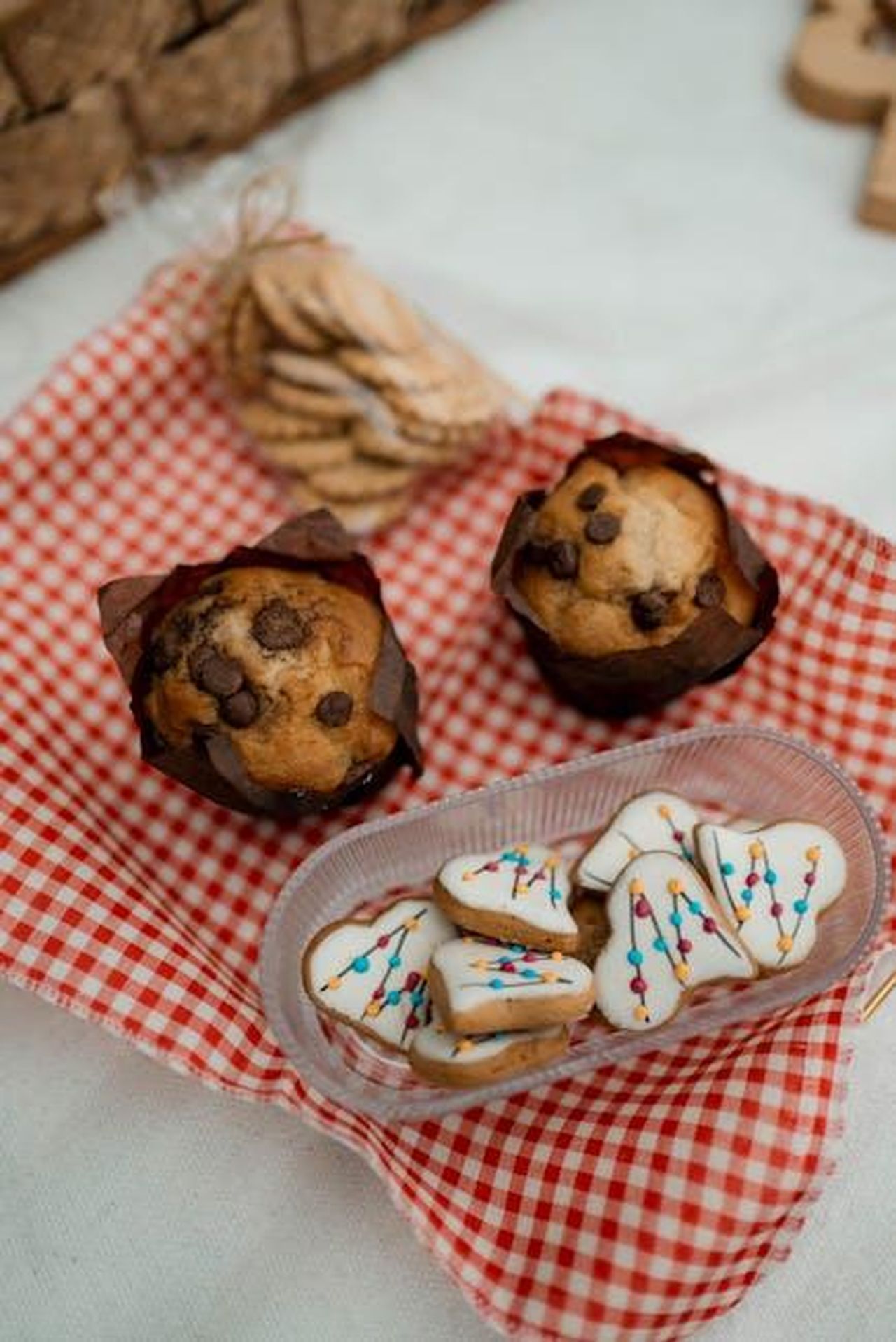 La_disconnessione_nella_cucina_delle_celebrit_KPC50Zcx8M - Confidenze24 Source: Jonathan Borba - pexels - Chocolate chip muffins paired with festive tree-shaped cookies on a checkered cloth.