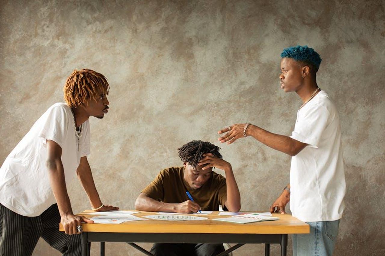 La_faida_tra_Bhad_Bhabie_e_Alabama_Barker_A6rpmCvoLg - Confidenze24 Source: Monstera Production - pexels - Three men in heated discussion around a table with documents, expressing emotions and ideas.