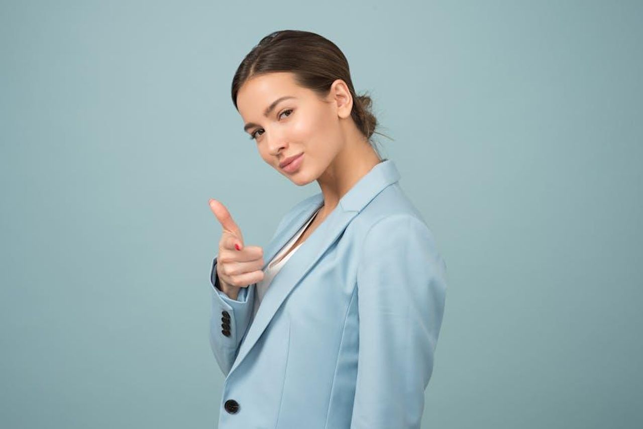 La_fiducia_di_Heather_Rae_El_Moussa_whgWT7oNnu - Confidenze24 Source: Moose Photos - pexels - A young woman in a blue suit exhibits confidence with a relaxed pose against a blue background.