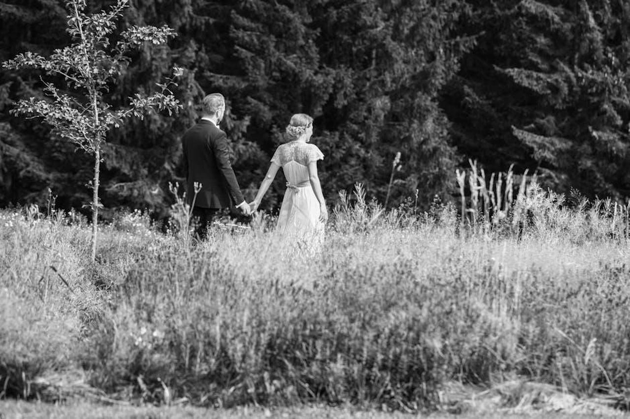 La_loro_storia_damore_e_la_famiglia_Si4rhIJZlU - Confidenze24 Source: Diana Leistikow - pexels - A couple holding hands, walking through a natural landscape in black and white.