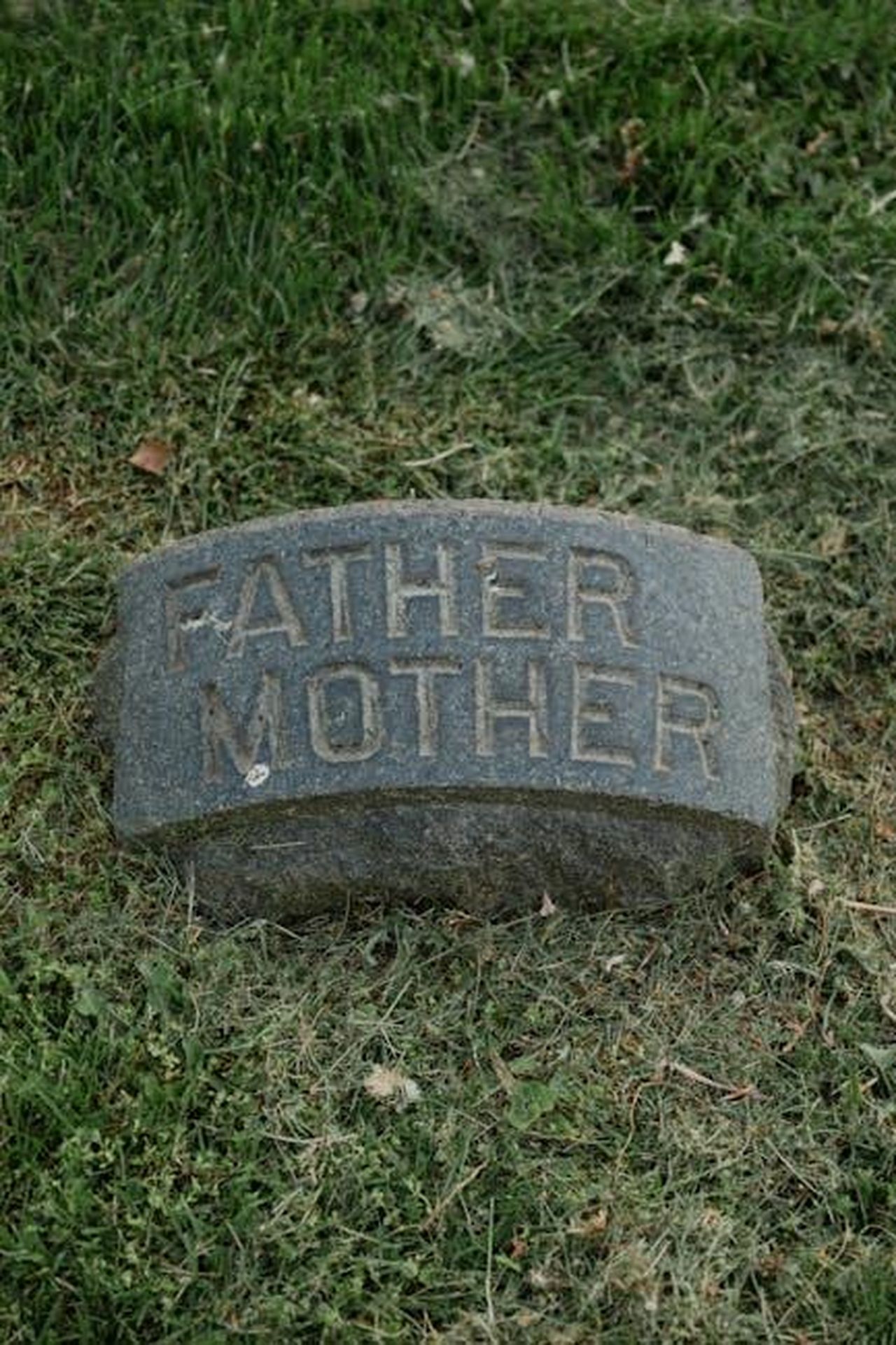 La_morte_della_madre_di_Stephen_1Z9yE3oHdN - Confidenze24 Source: RDNE Stock project - pexels - A gravestone with 'Father Mother' text on grass, symbolizing remembrance.