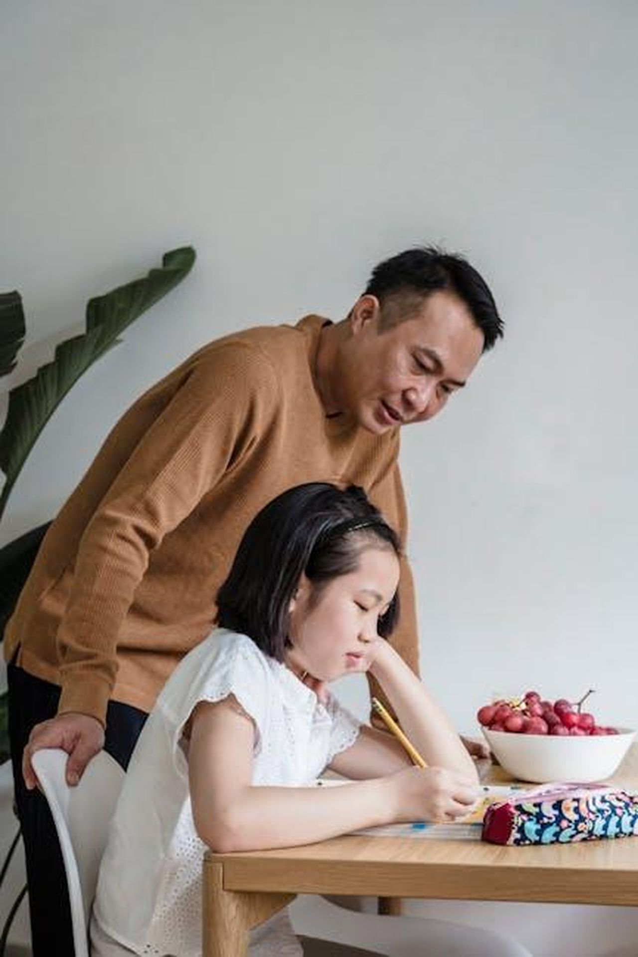 La_percezione_sociale_dei_padri_mk9LLY2rYW - Confidenze24 Source: Annushka Ahuja - pexels - Father helping his daughter with homework at the dining table, creating a supportive learning environment.