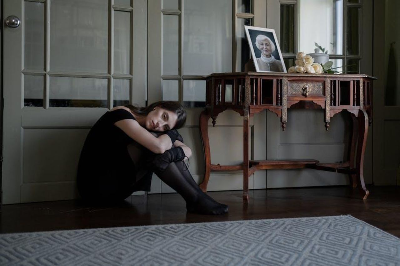La_perdita_che_ha_ispirato_il_nome_di_Eric_1h9SQCfgIR - Confidenze24 Source: cottonbro studio - pexels - A solitary woman in black attire sits on the floor in mourning inside her home.