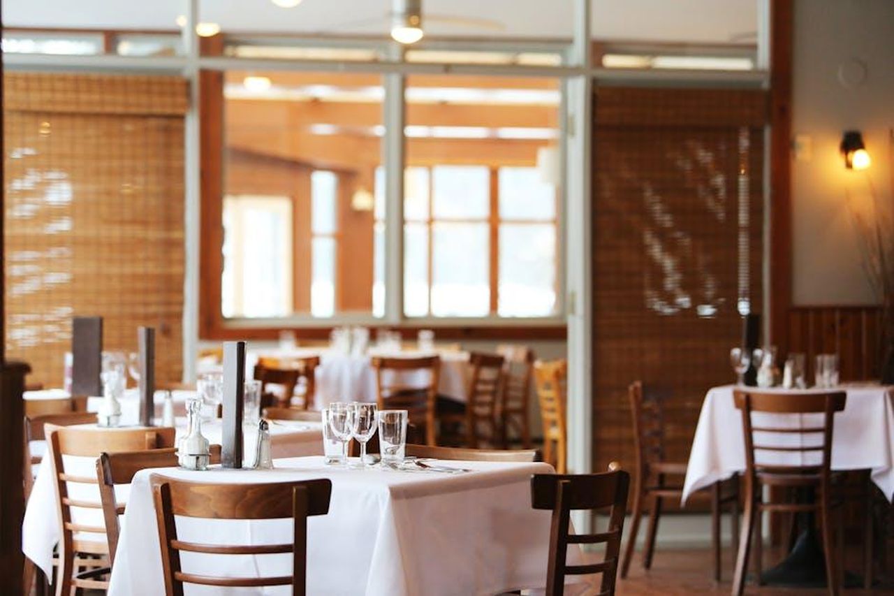 La_polemica_del_ristorante_sXkjZvyIug - Confidenze24 Source: Life Of Pix - pexels - A serene restaurant interior with wooden chairs and tables set with glasses, ready for dining.