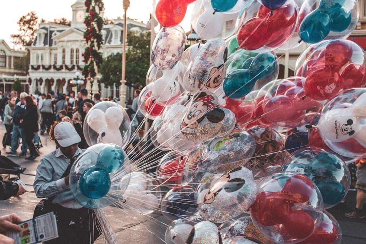 La_popolarit_della_collezione_e_la_disponibilit_vD1gZlBG32 - Confidenze24 Source: Craig Adderley - pexels - Colorful Mickey and Minnie balloons at a bustling theme park street.