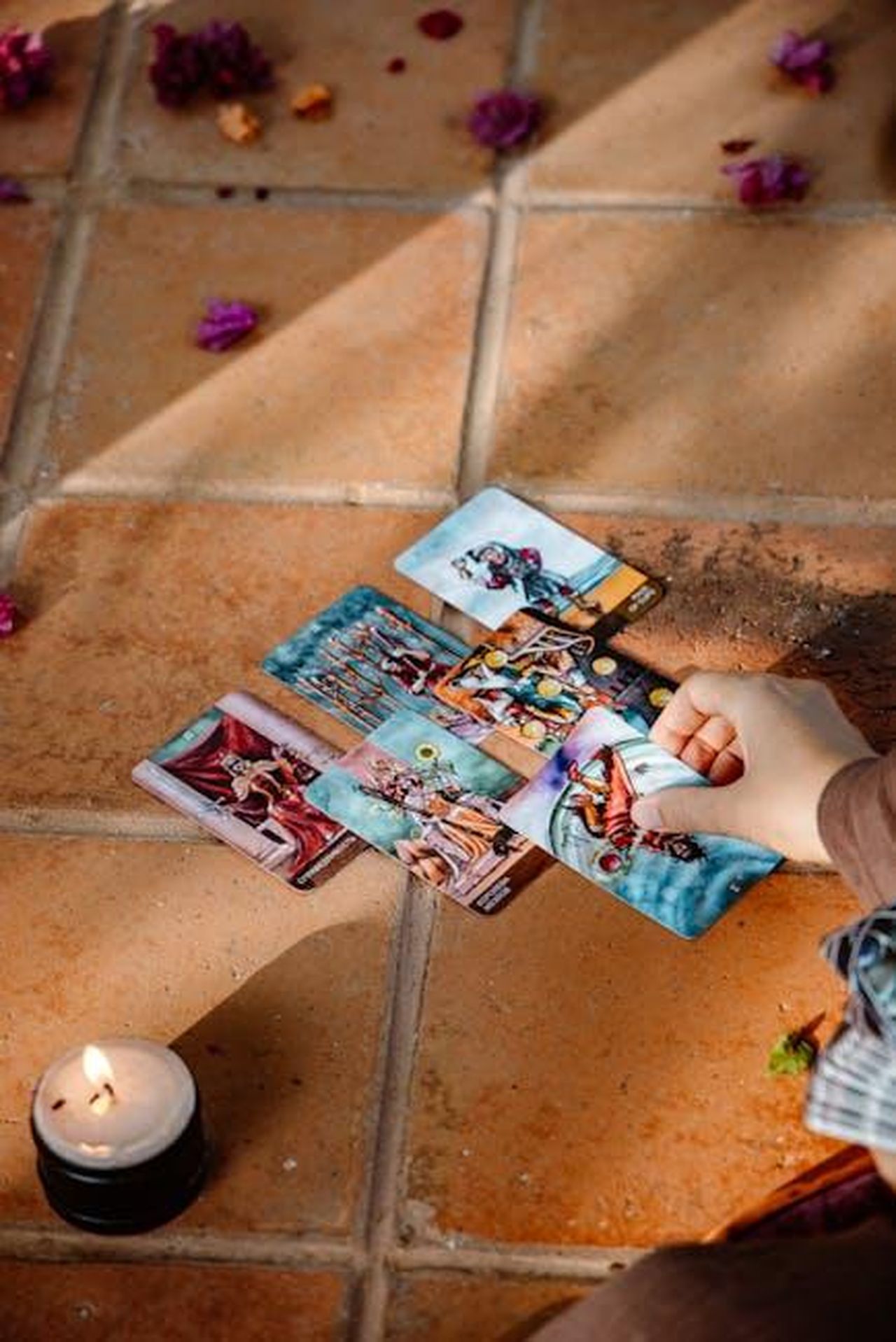 La_previsione_di_Macaulay_sulla_vittoria_di_Kieran_yNrwyaBhoT - Confidenze24 Source: ROMAN ODINTSOV - pexels - A hand arranging tarot cards on a tiled floor next to a lit candle, conveying mystery.
