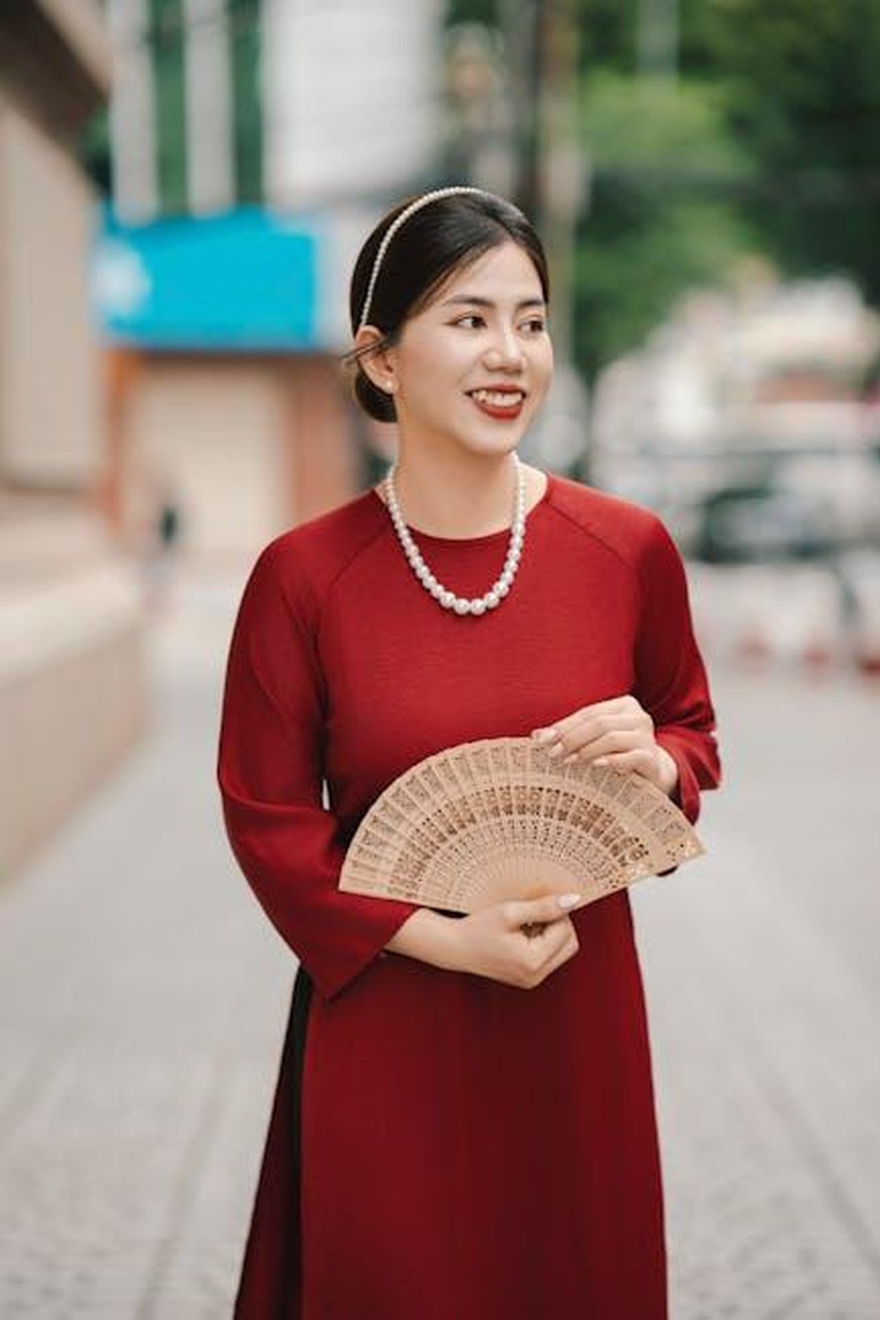 La_reazione_dei_fan_e_il_malinteso_XGZMlfqXmL - Confidenze24 Source: nguyen kha - pexels - Portrait of a smiling woman in a red dress holding a fan, outdoors.