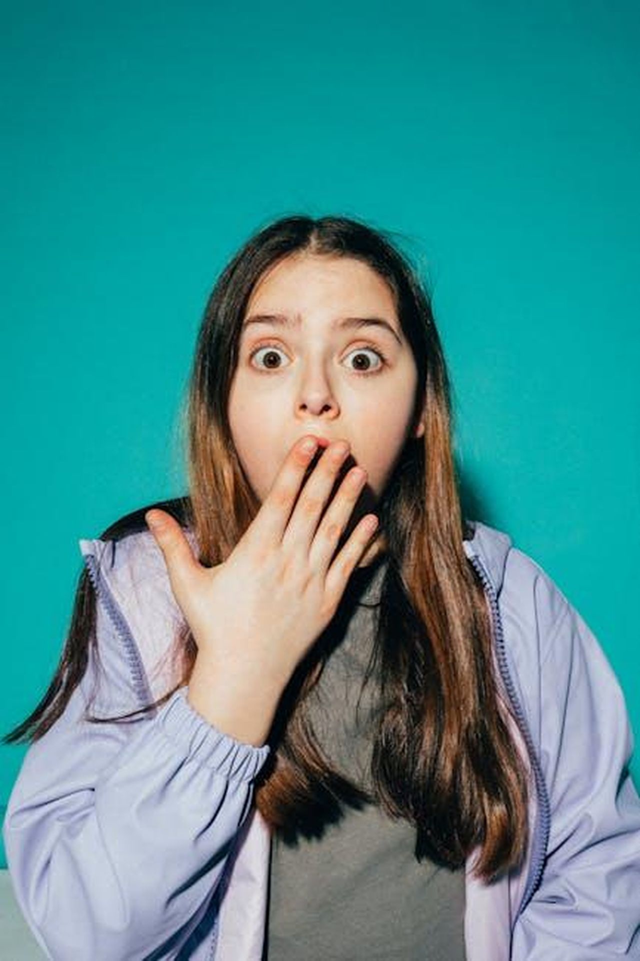 La_reazione_della_moglie_di_Cameron_al_film_9u0C1PUMY6 - Confidenze24 Source: KoolShooters - pexels - A young girl looks shocked with her hand on her mouth against a teal background.