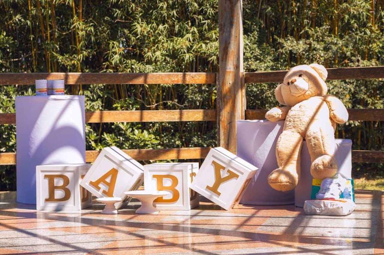 La_reazione_di_Machine_Gun_Kelly_alla_nascita_della_figlia_ziJviKhnvj - Confidenze24 Source: Leandro Bezerra - pexels - Charming outdoor baby shower setup with teddy bear and decor boxes spelling 'BABY'.