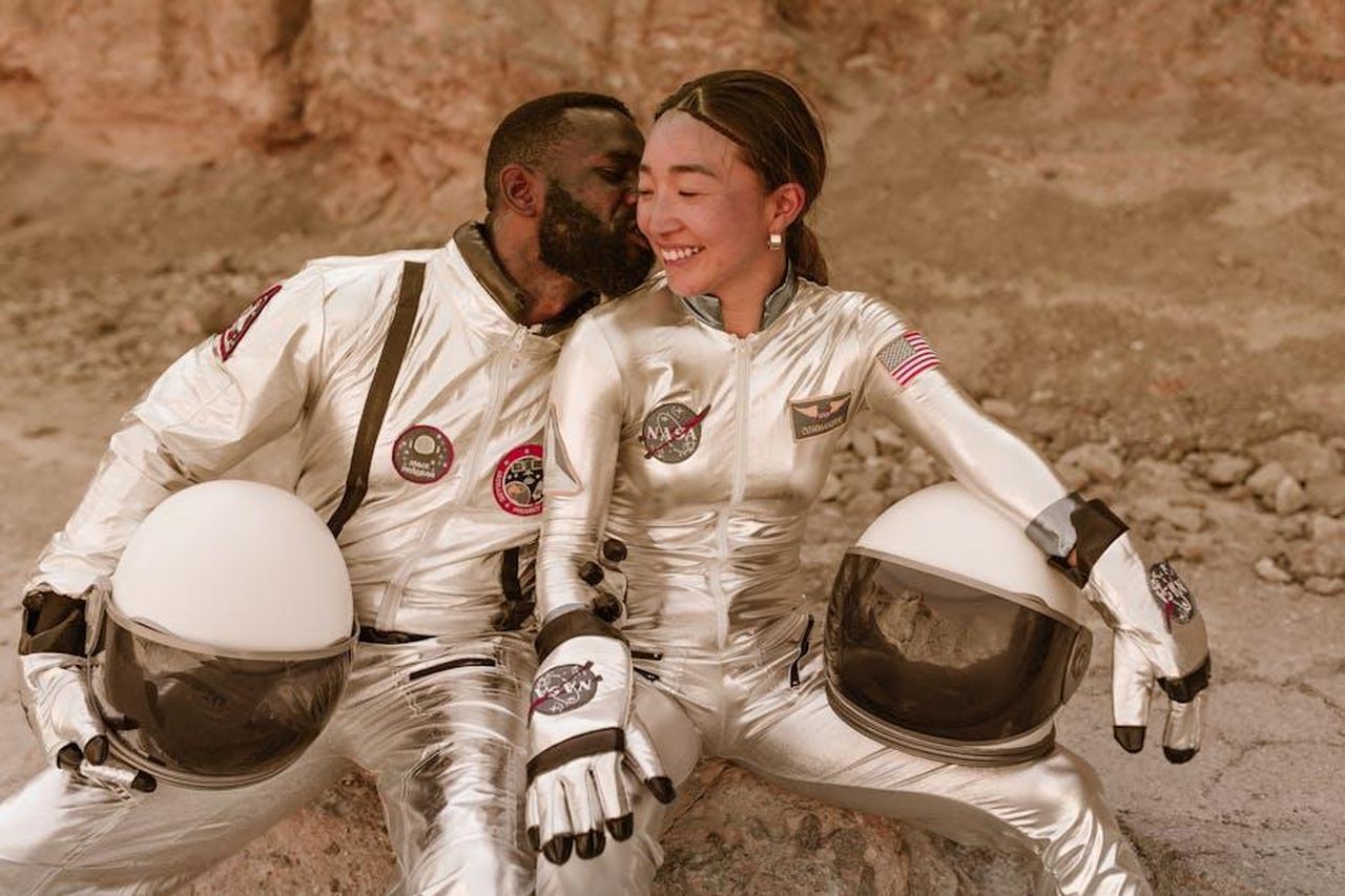La_relazione_tra_Cole_Hauser_e_Ben_Affleck_3JZDJKyPmC - Confidenze24 Source: RDNE Stock project - pexels - Interracial couple in silver astronaut costumes sharing a kiss on a rocky terrain, evoking space exploration romance.