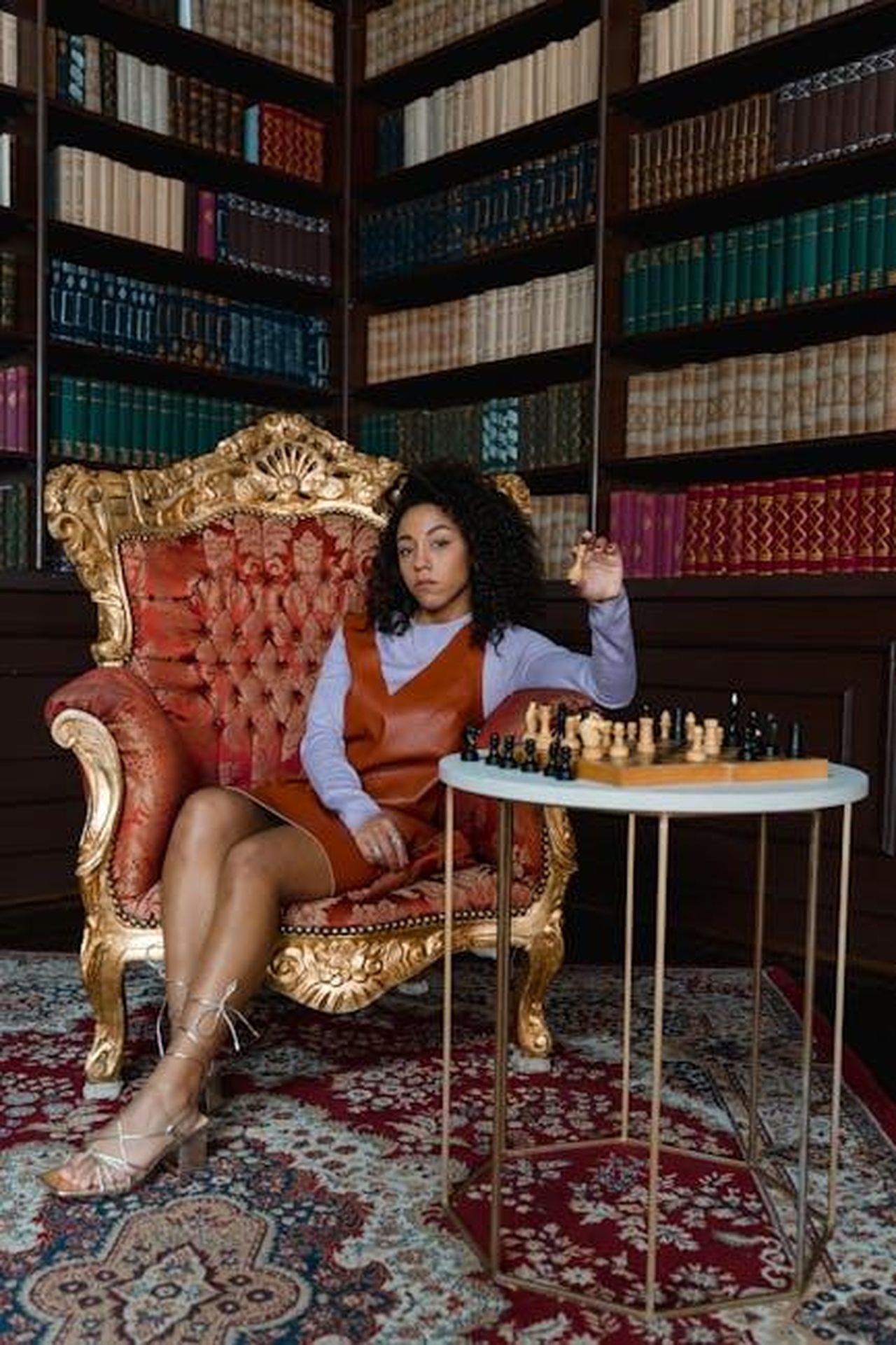 La_reputazione_di_Camilla_e_il_suo_impatto_sulla_famiglia_reale_rCqvPQ1WFY - Confidenze24 Source: Tima Miroshnichenko - pexels - A thoughtful woman sitting in a luxurious library playing chess, strategizing her next move.