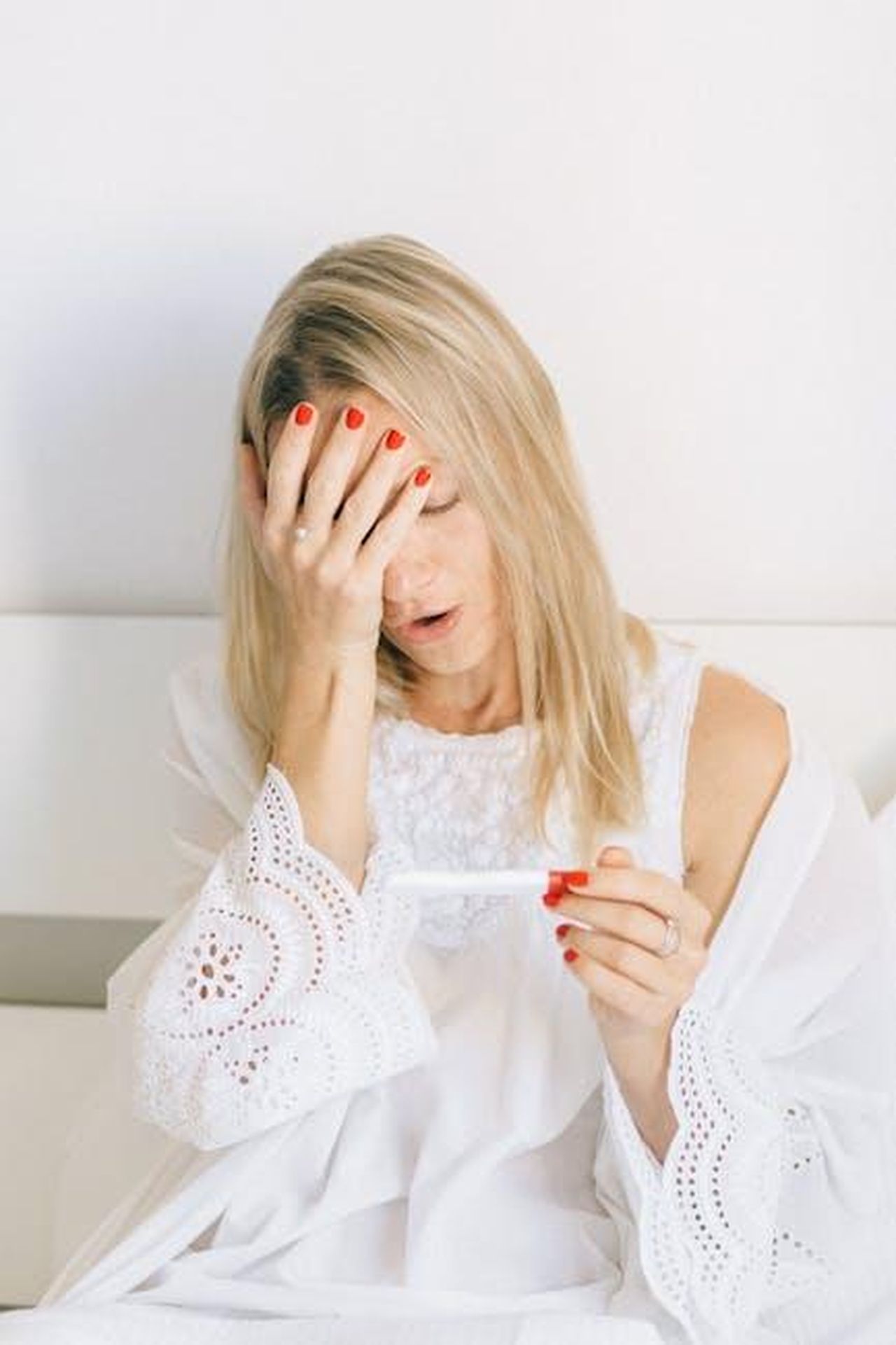 La_risposta_di_Jackiey_BKY3gtdH2Y - Confidenze24 Source: Nataliya Vaitkevich - pexels - A woman in a white robe holds a pregnancy test with a surprised expression, conveying emotion and anticipation.