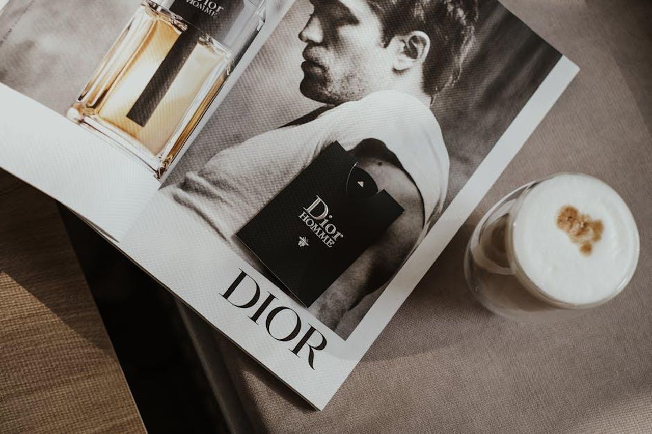 La_risposta_di_Meghan_e_la_sua_strategia_promozionale_7eJX9yhwS0 - Confidenze24 Source: Valeriia Miller - pexels - Elegant flat lay featuring a Dior magazine and a stylish coffee, suggesting luxury and sophistication.
