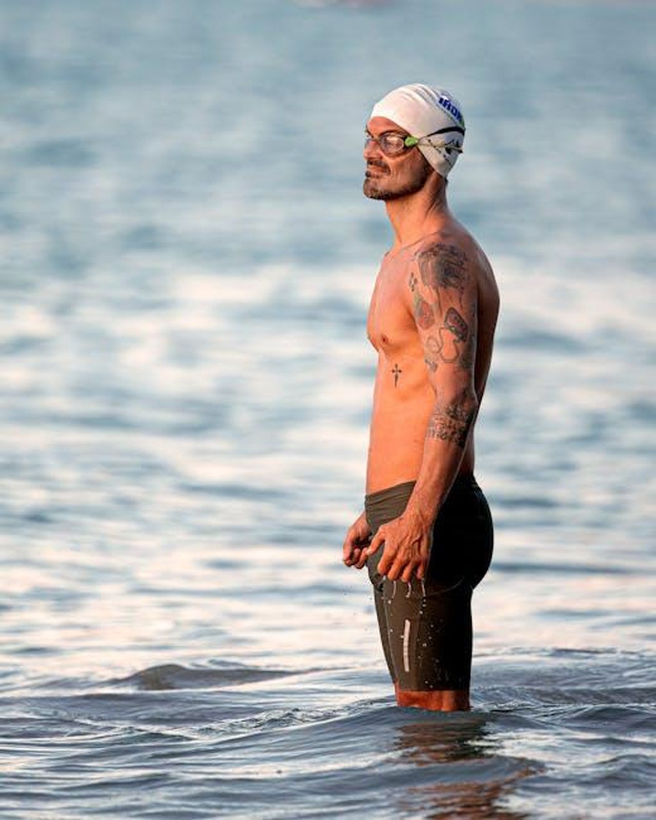 La_routine_di_allenamento_di_Randall_Park_t2Yi4EdxOZ - Confidenze24 Source: Eduardo Holanda - pexels - Tattooed male swimmer standing in ocean water wearing swim goggles and cap.
