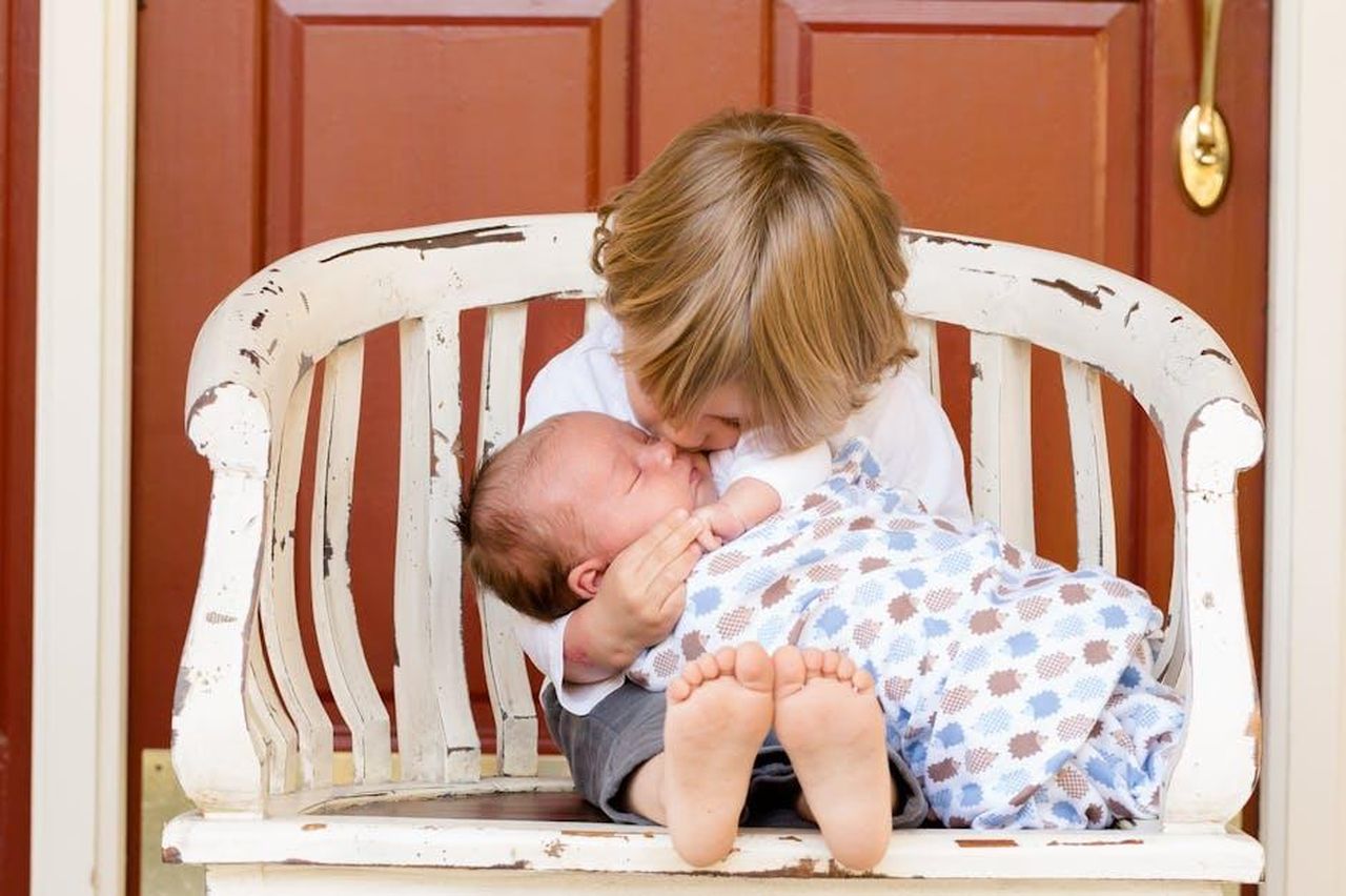 La_scoperta_di_nuovi_fratelli_tramite_i_social_media_0eOMpq3MSl - Confidenze24 Source: Pixabay - pexels - A tender moment captured between an older sibling and newborn, embracing love and family bonds.